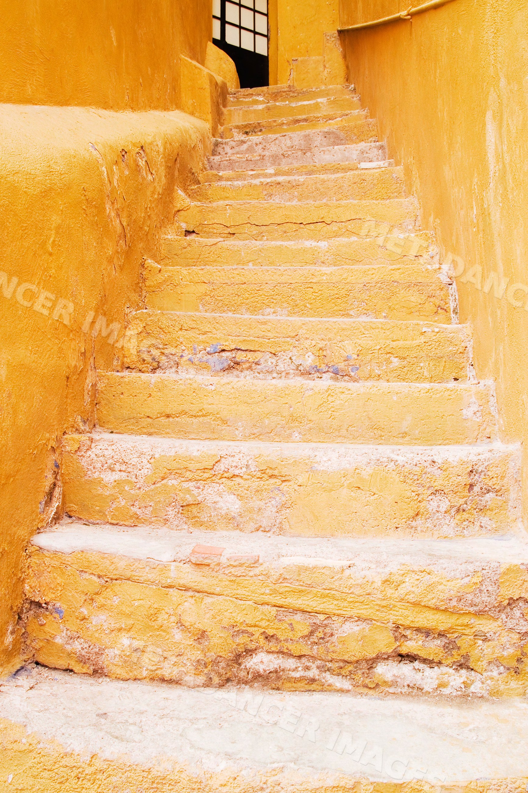 Yellow weathered stone steps leading to an open doorway, mexico