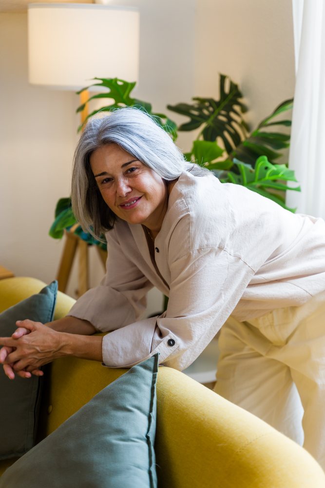 White woman leaning on yellow sofa in cozy living room