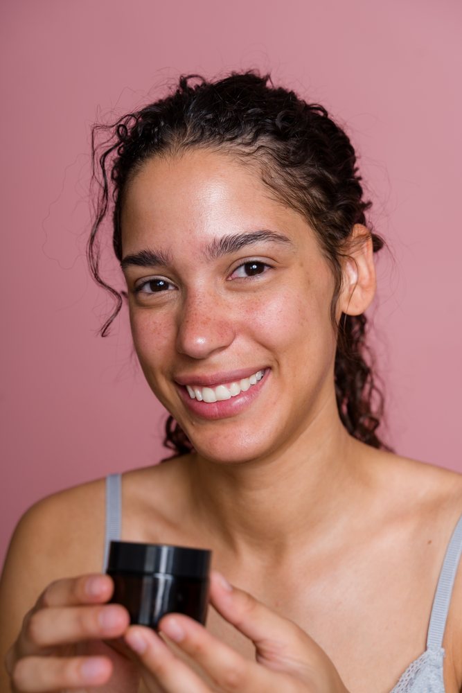 Hispanic woman holding cosmetic jar smiling in beauty shoot in Spain