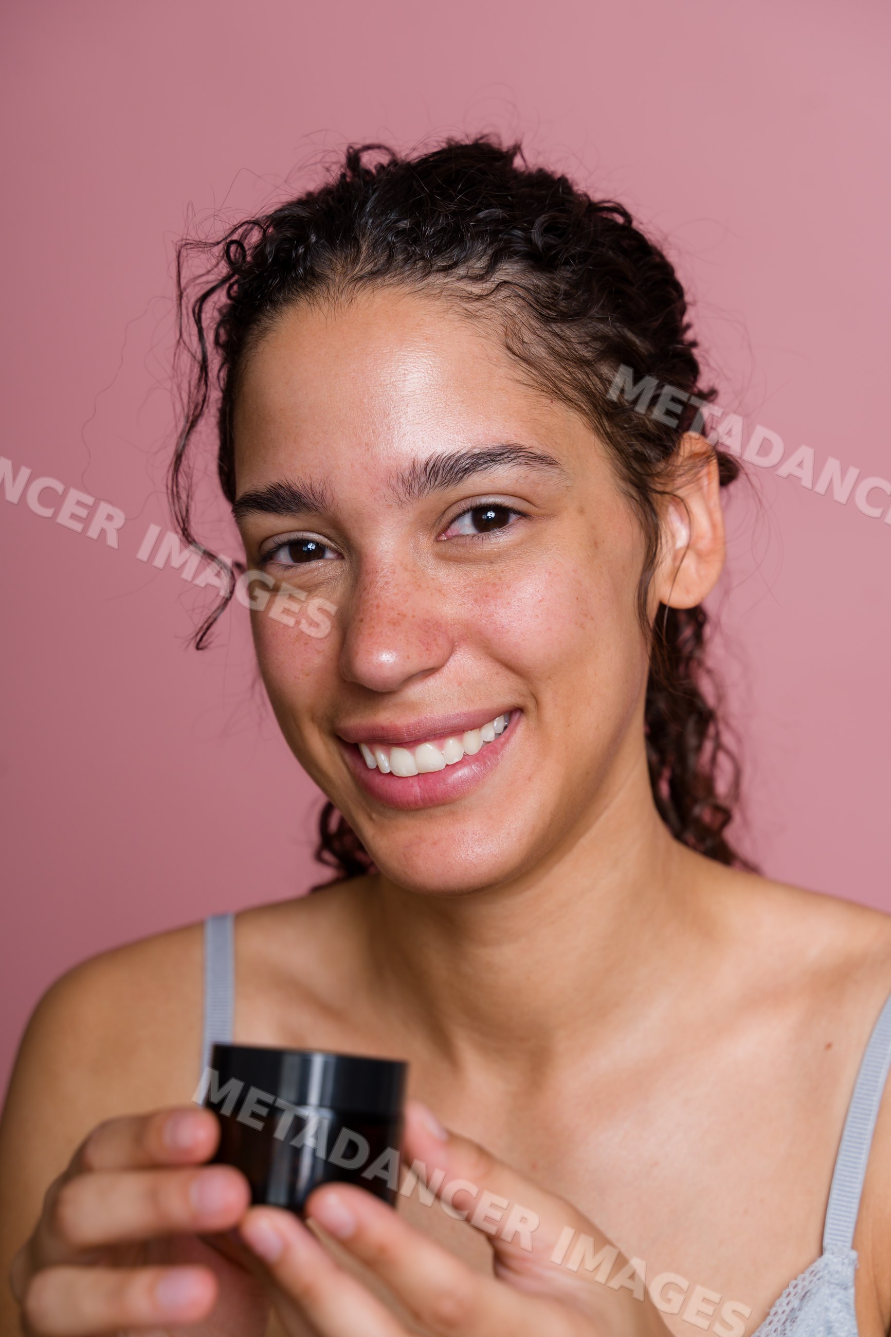 Hispanic woman holding cosmetic jar smiling in beauty shoot in Spain