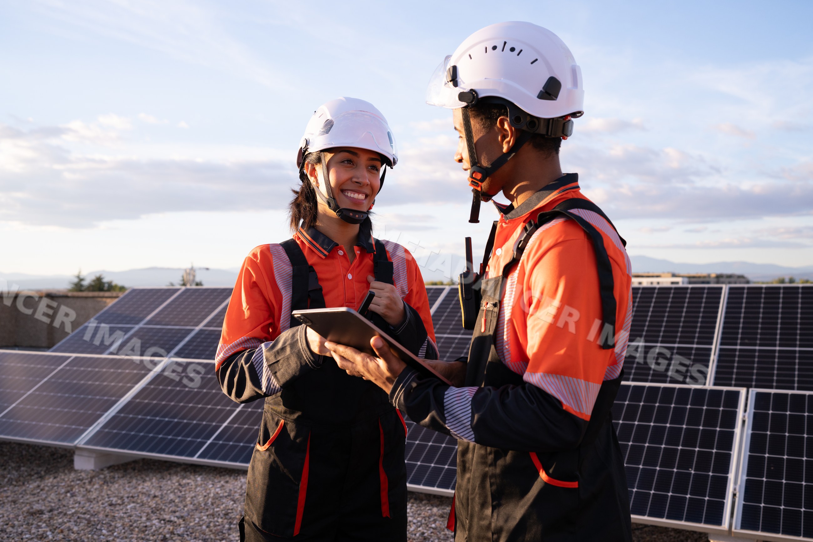 Hispanic workers discussing solar panel installation on a rooftop