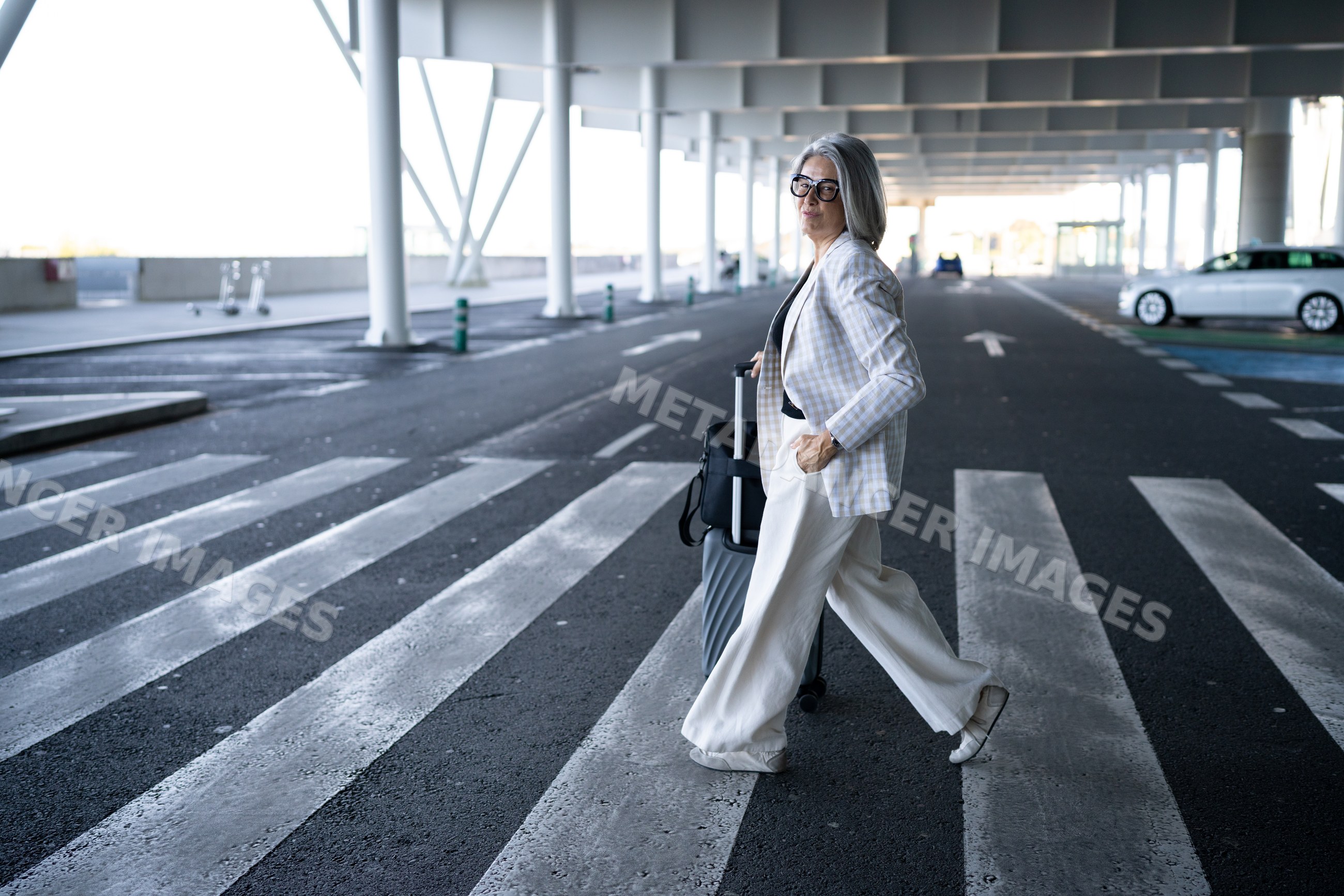 White woman walking with luggage on urban pedestrian crossing