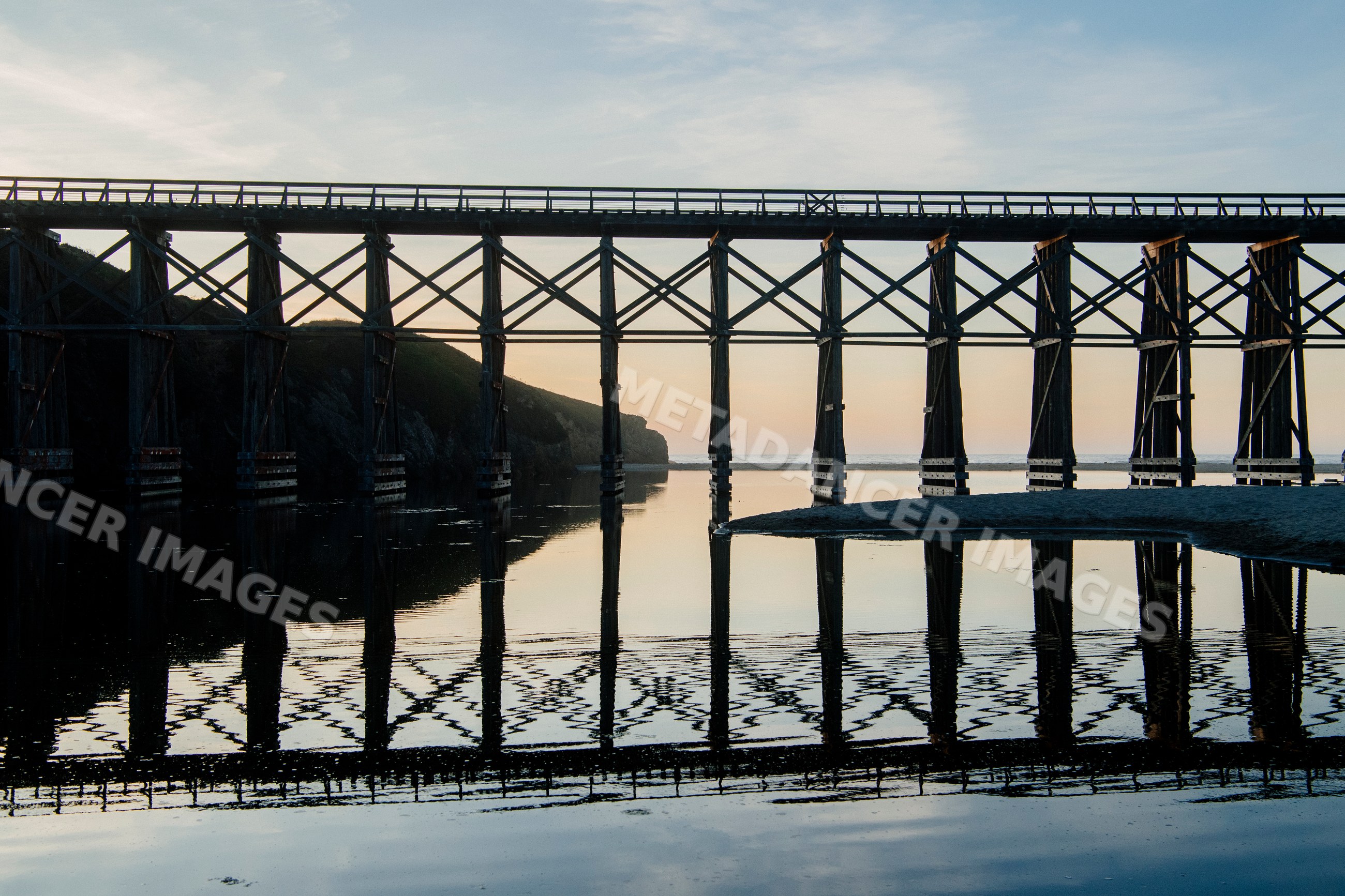 Wooden bridge reflecting over water at sunset California USA
