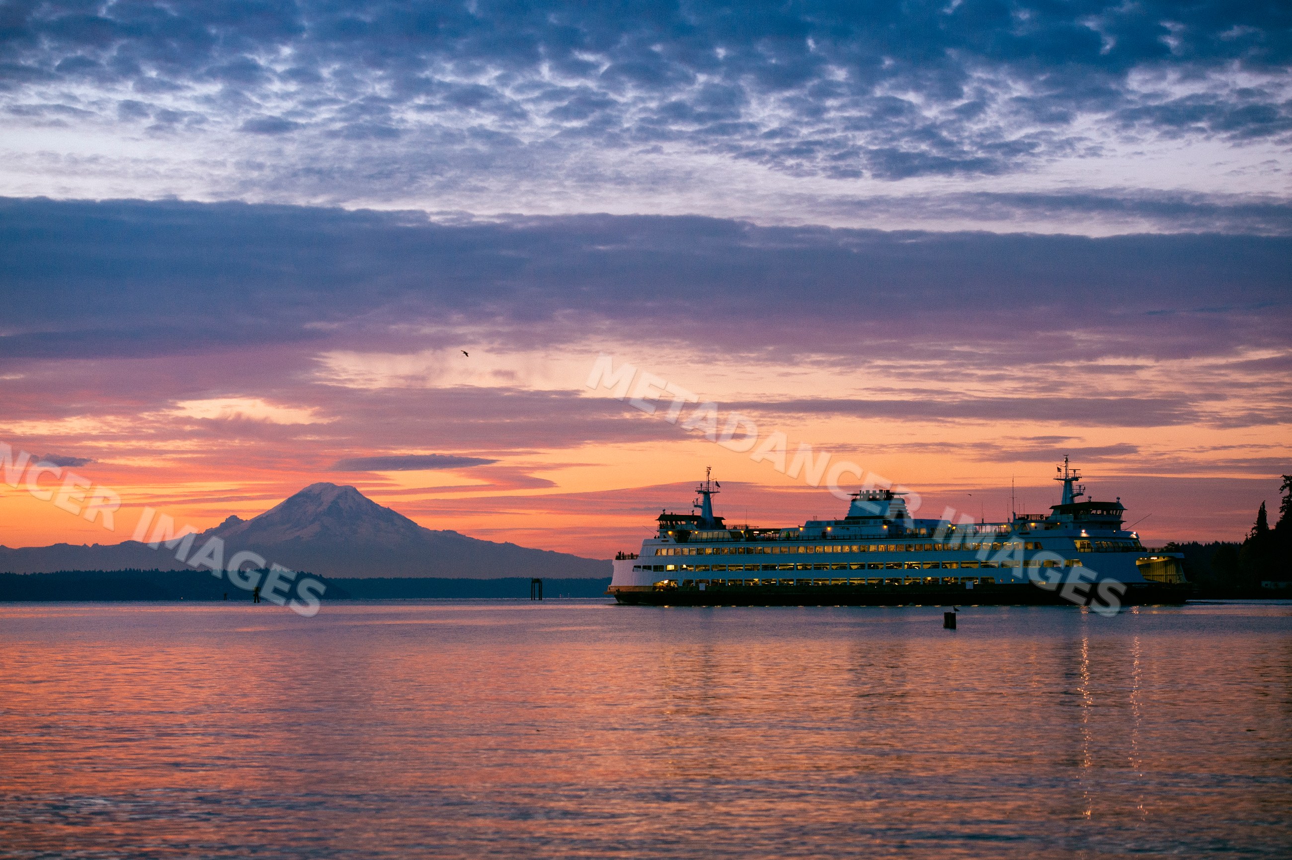 Seattle ferry sailing at sunset with mount rainier in background