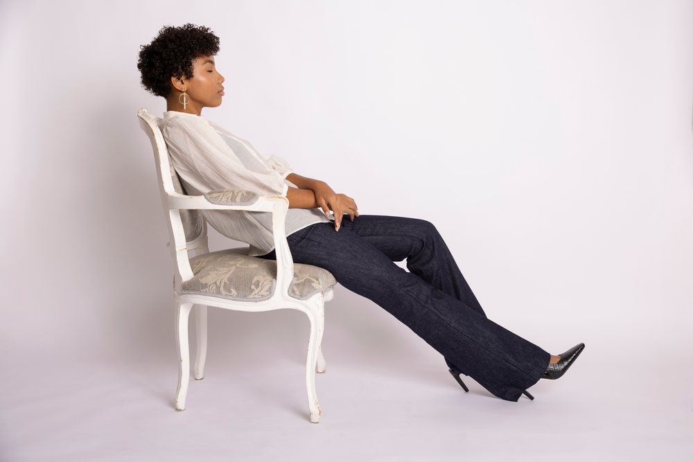 Hispanic woman sitting in vintage chair with white blouse and jeans