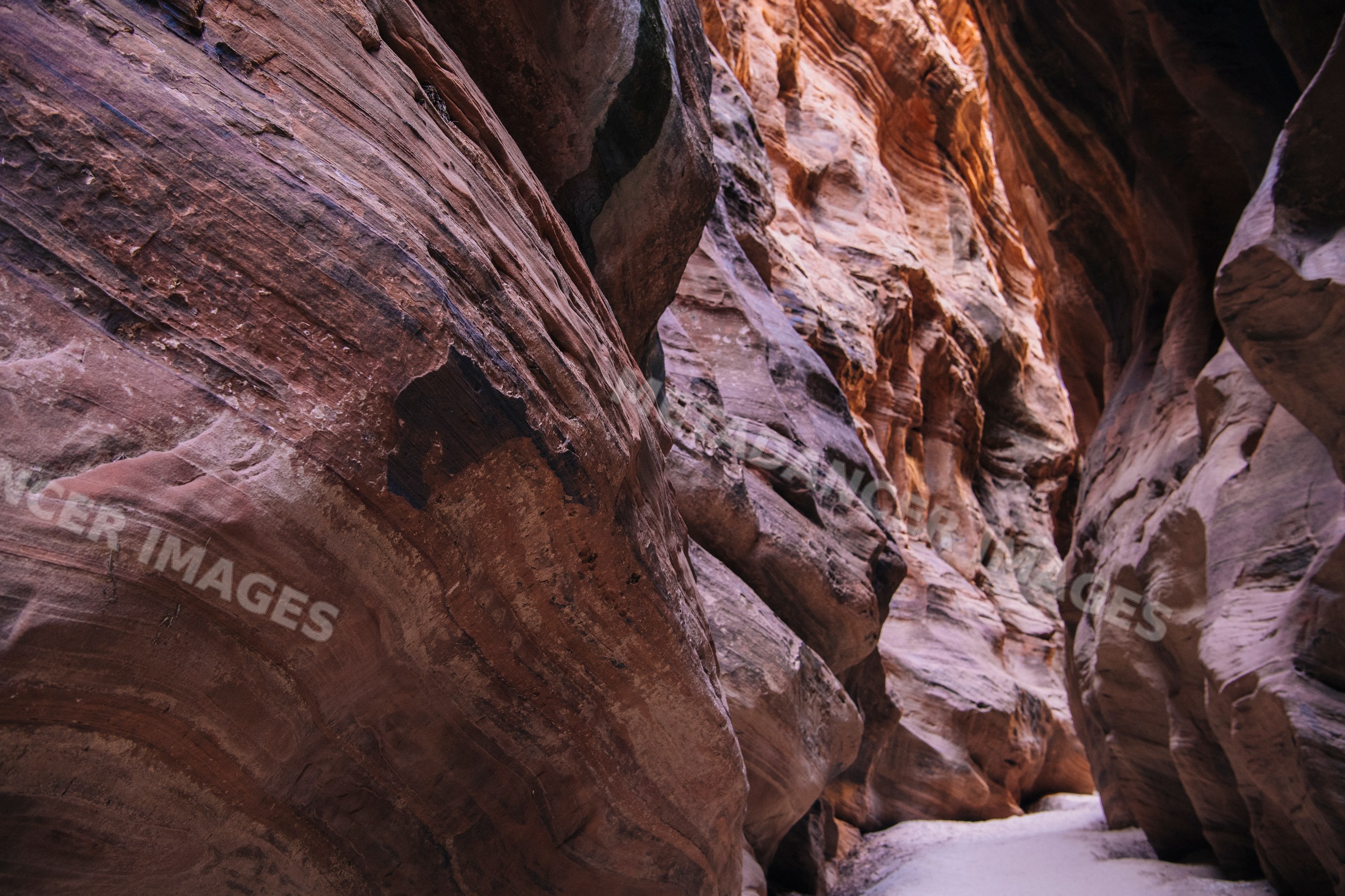 Natural rock formations in narrow slot canyon with sand path in Utah