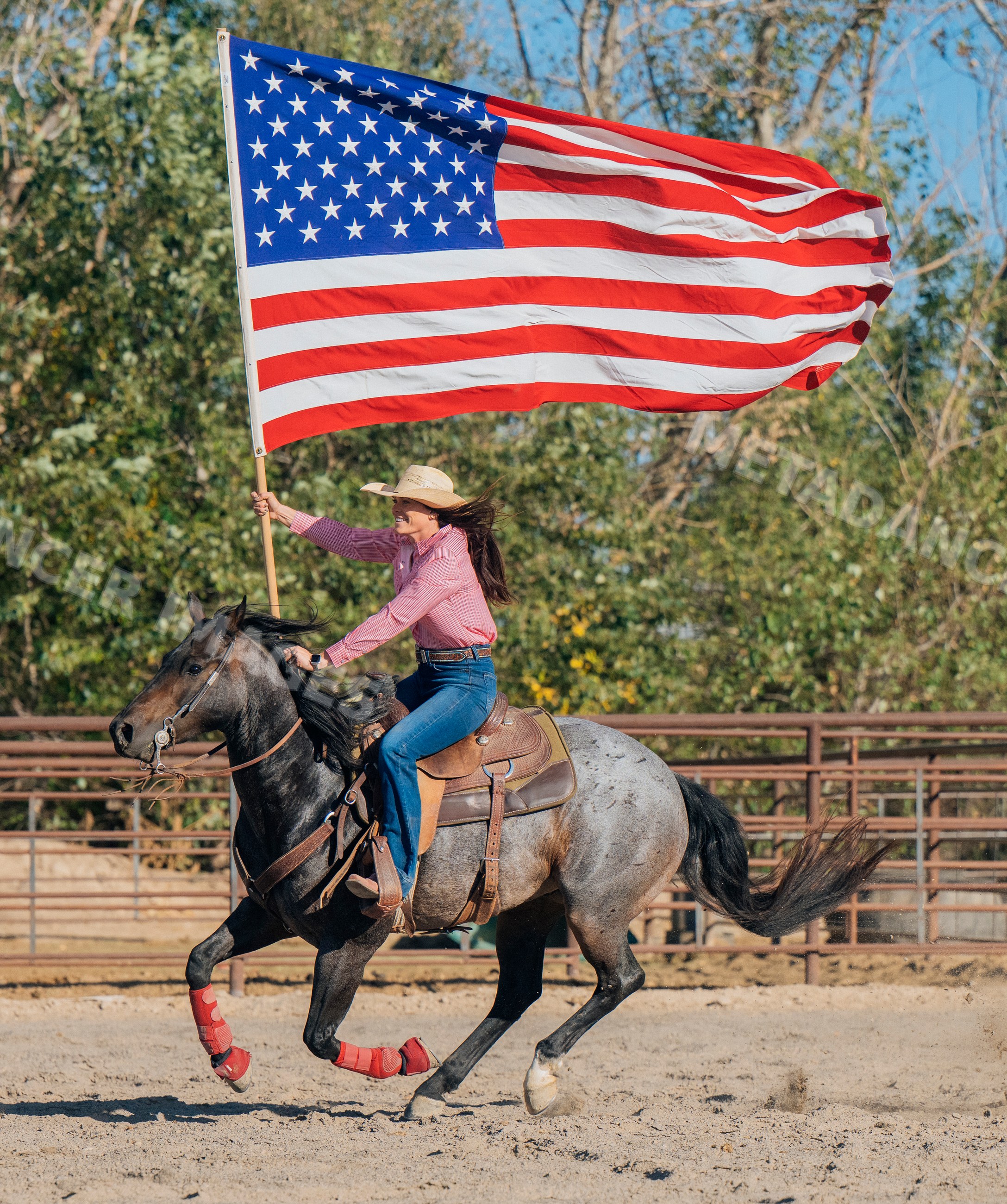 Female rider galloping horse carrying american flag in rodeo arena