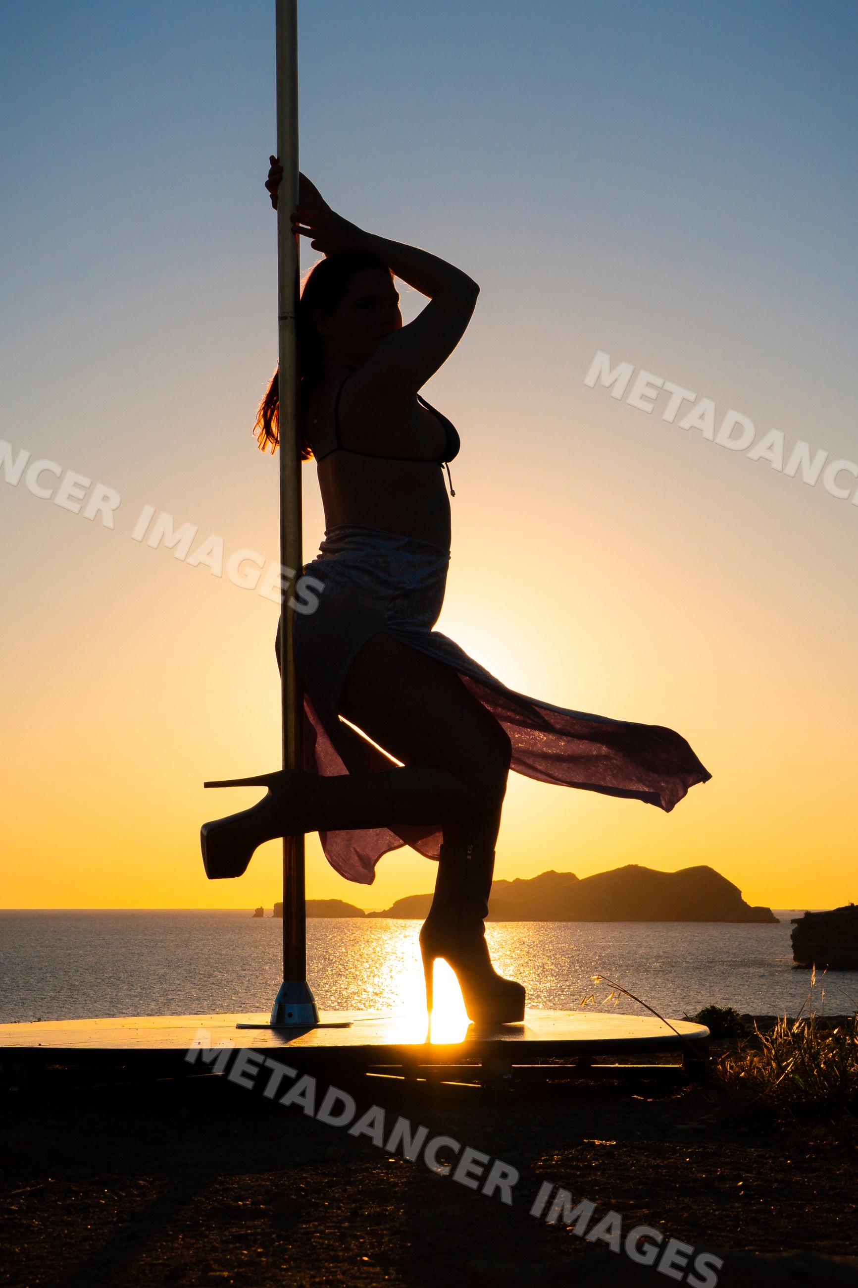 White woman performing pole dance silhouette at sunset in Ibiza, Spain