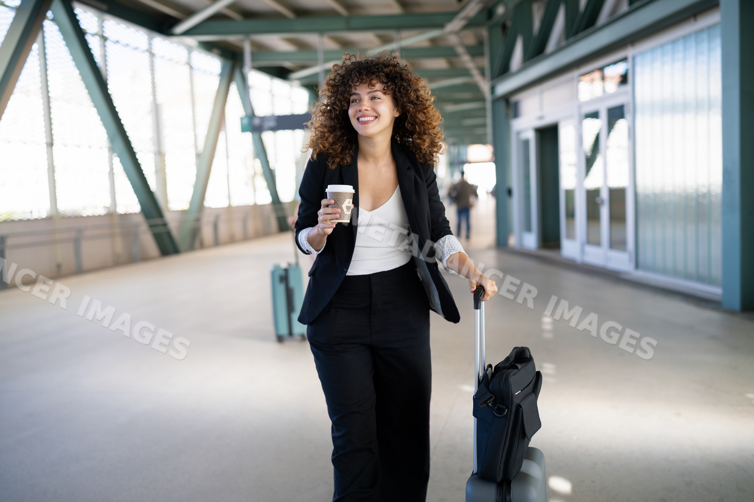 White woman walking with luggage and coffee