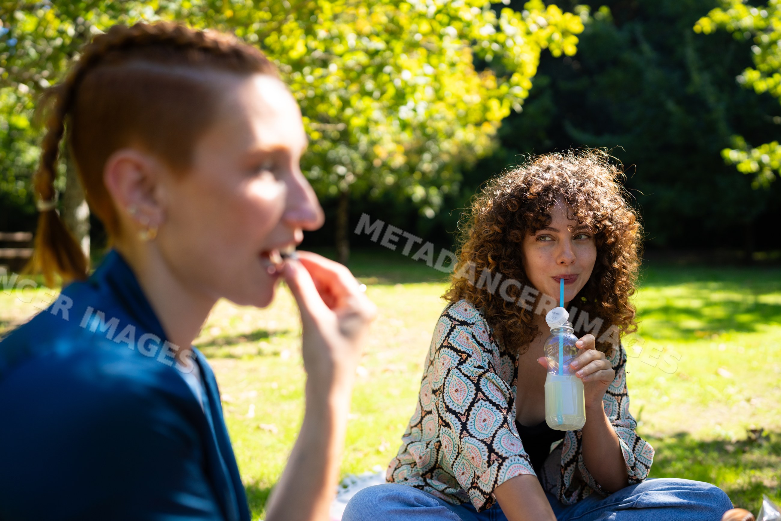 Two white and African American women enjoying a picnic in a sunny park