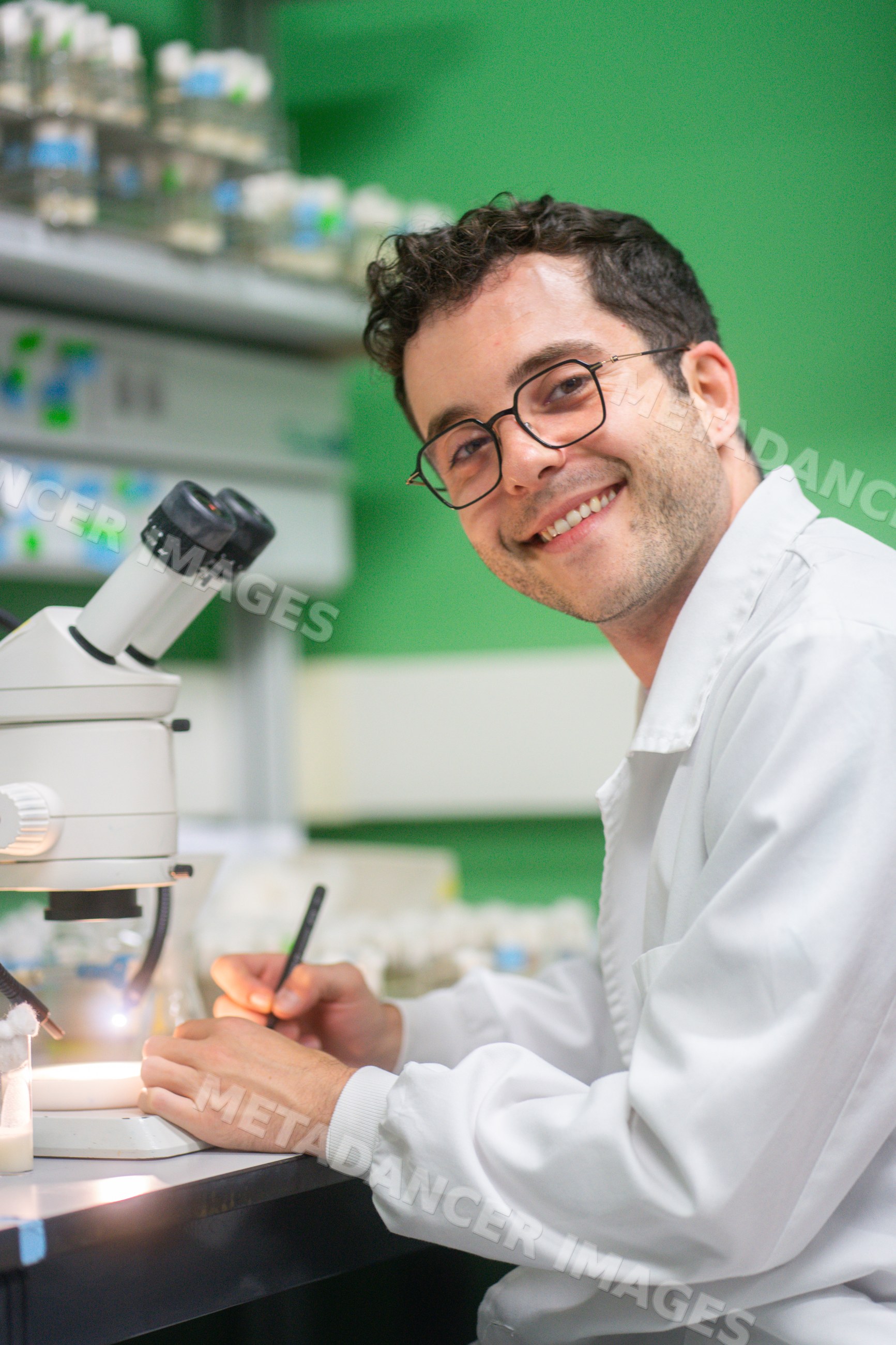 Male scientist writes notes beside a microscope