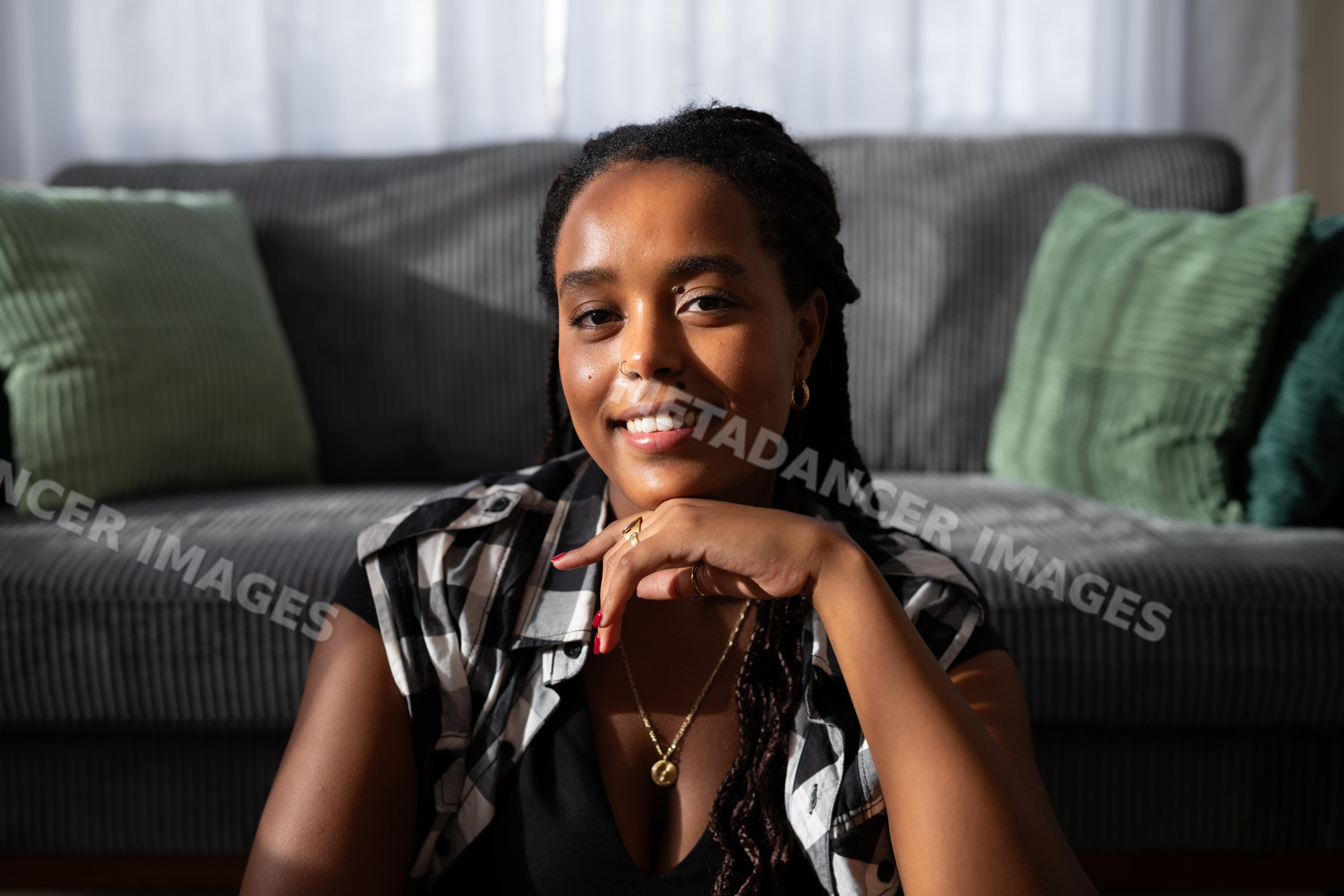 A young African American woman sitting indoors smiling warmly