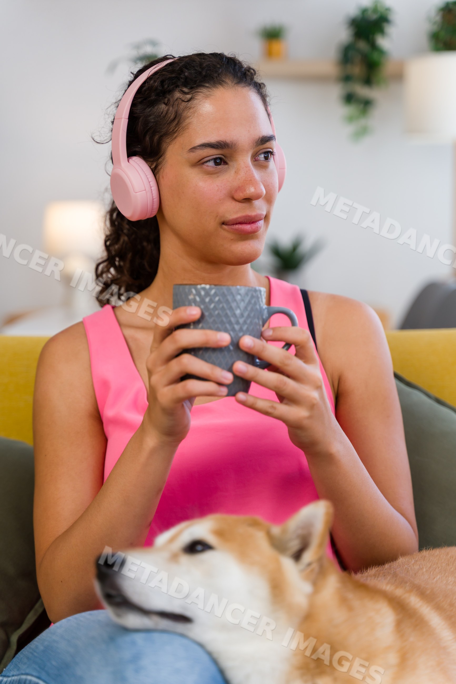A young Hispanic woman relaxes with her dog and coffee