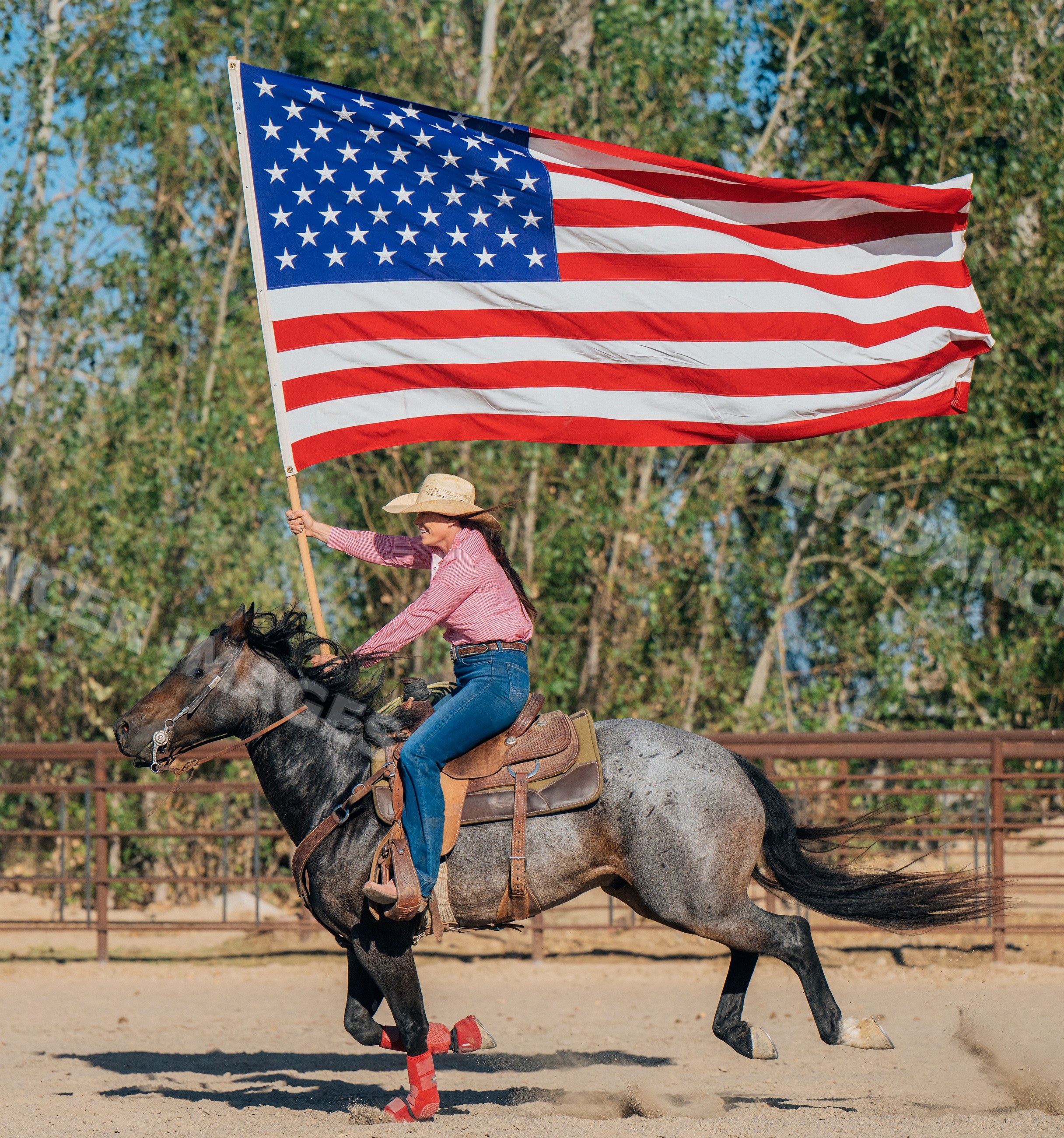 White woman riding horse carrying large american flag