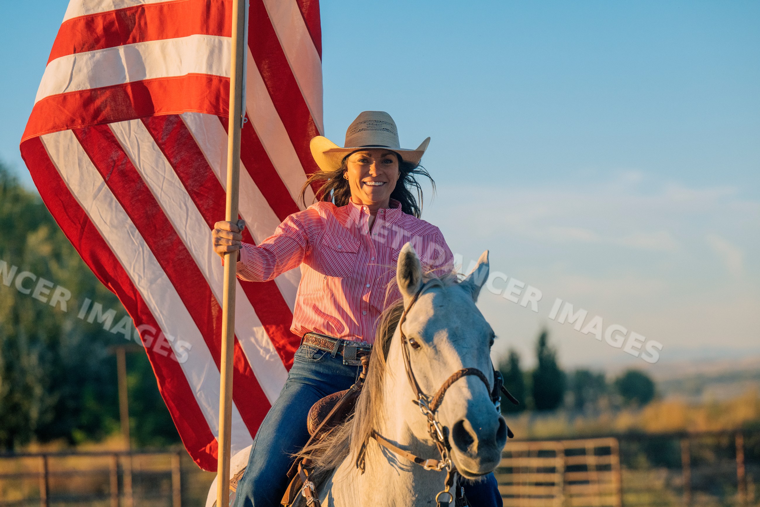 White woman horseback riding holding american flag