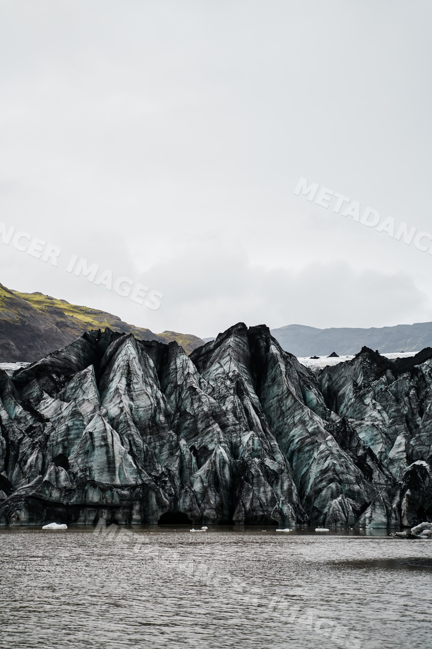 A melting glacier with ice peaks and volcanic ash in a glacial lake