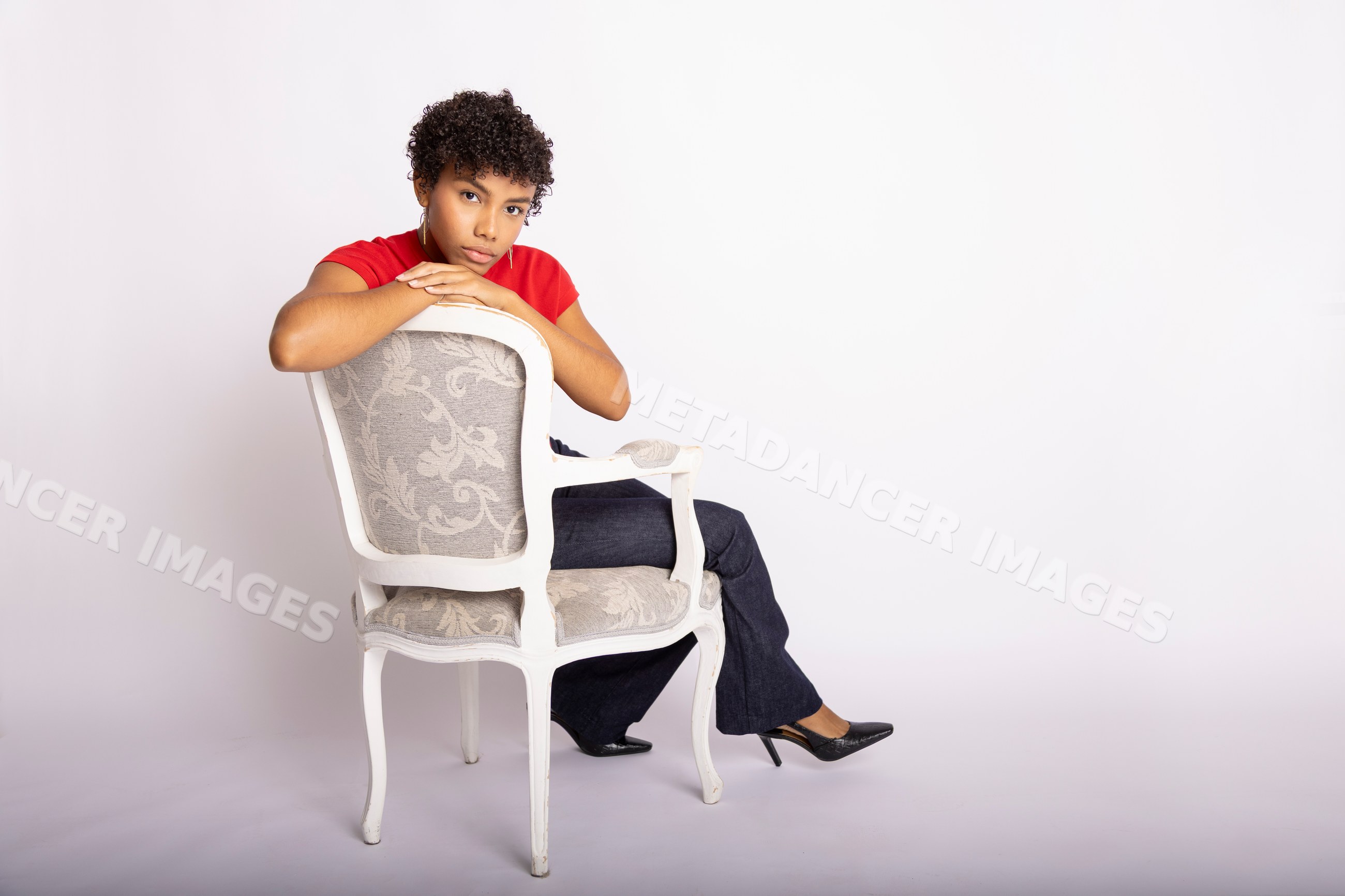 Young Hispanic woman seated backwards on white vintage chair