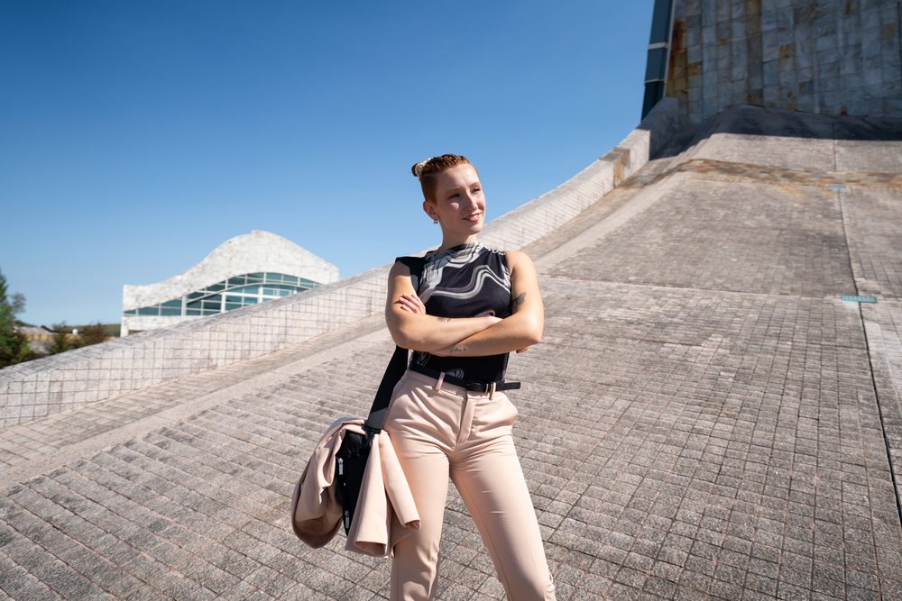 White woman standing confidently outdoors with modern architecture