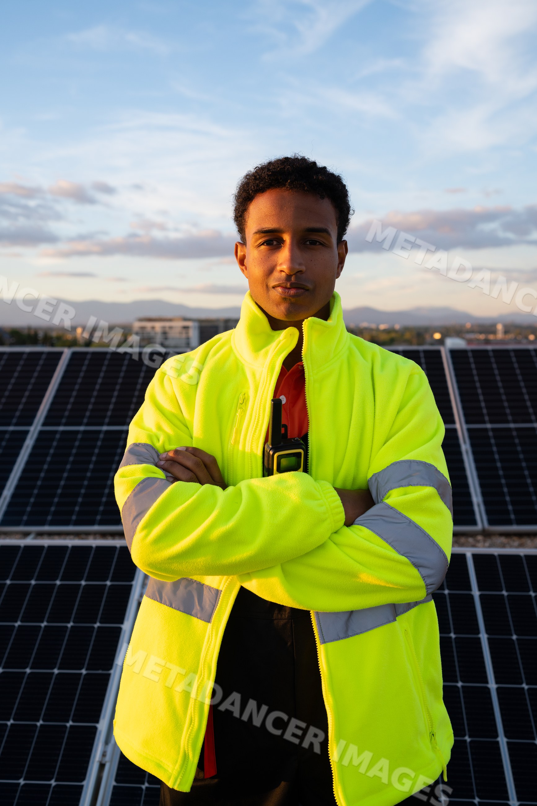 Man in high visibility jacket in front of solar panels at sunset