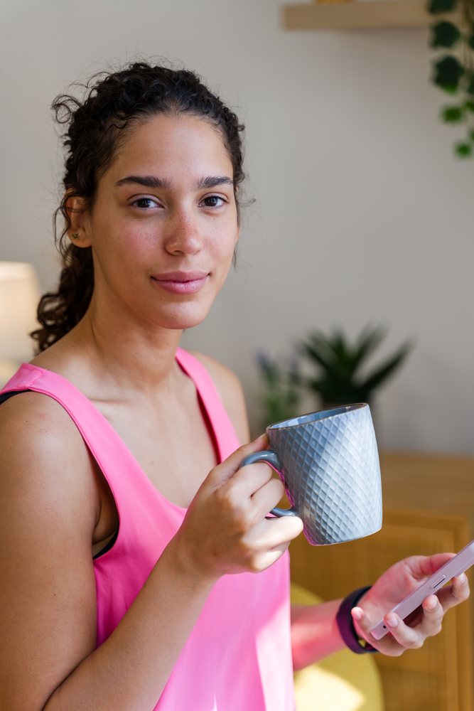 Young Hispanic woman holding a cup and smartphone