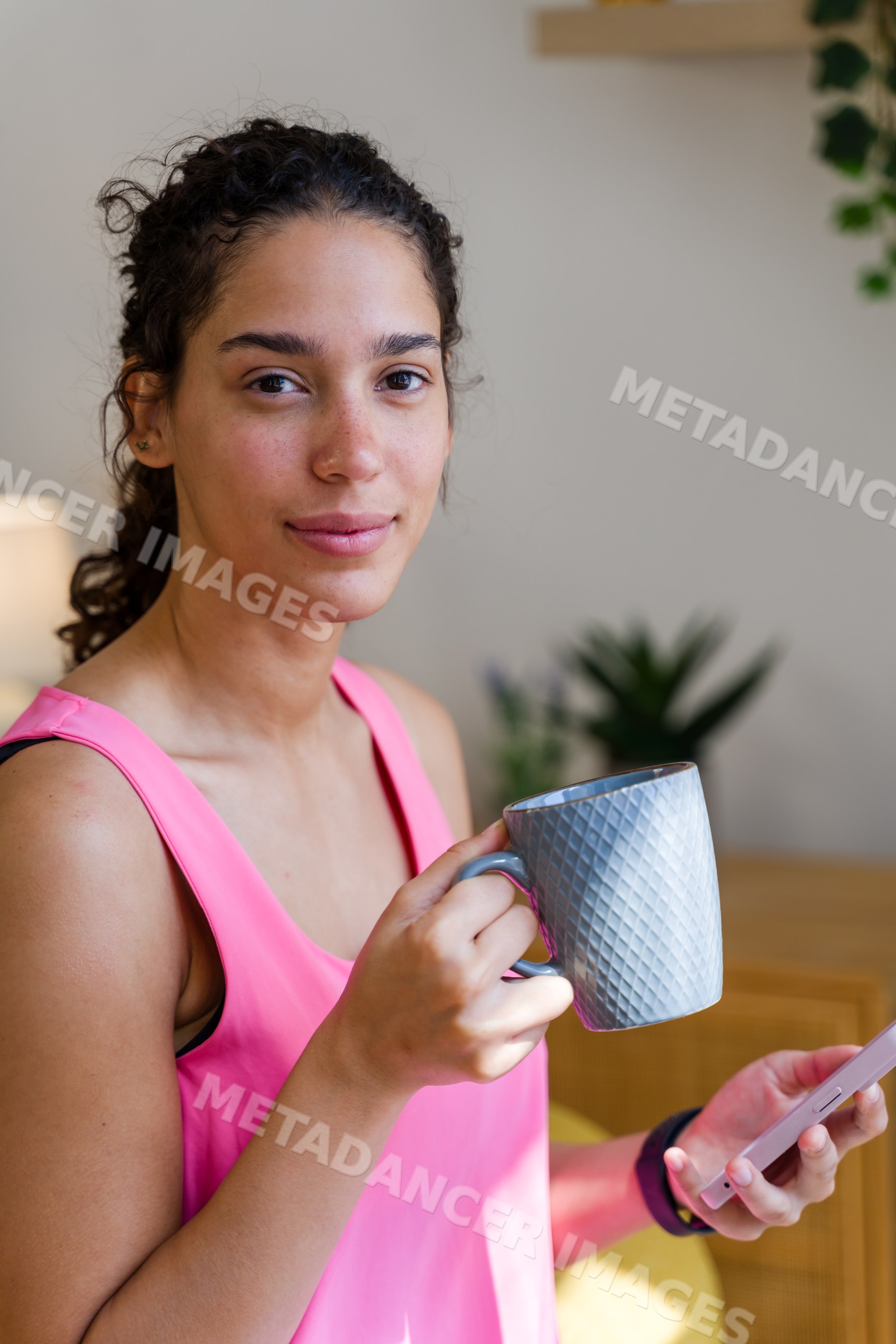 Young Hispanic woman holding a cup and smartphone