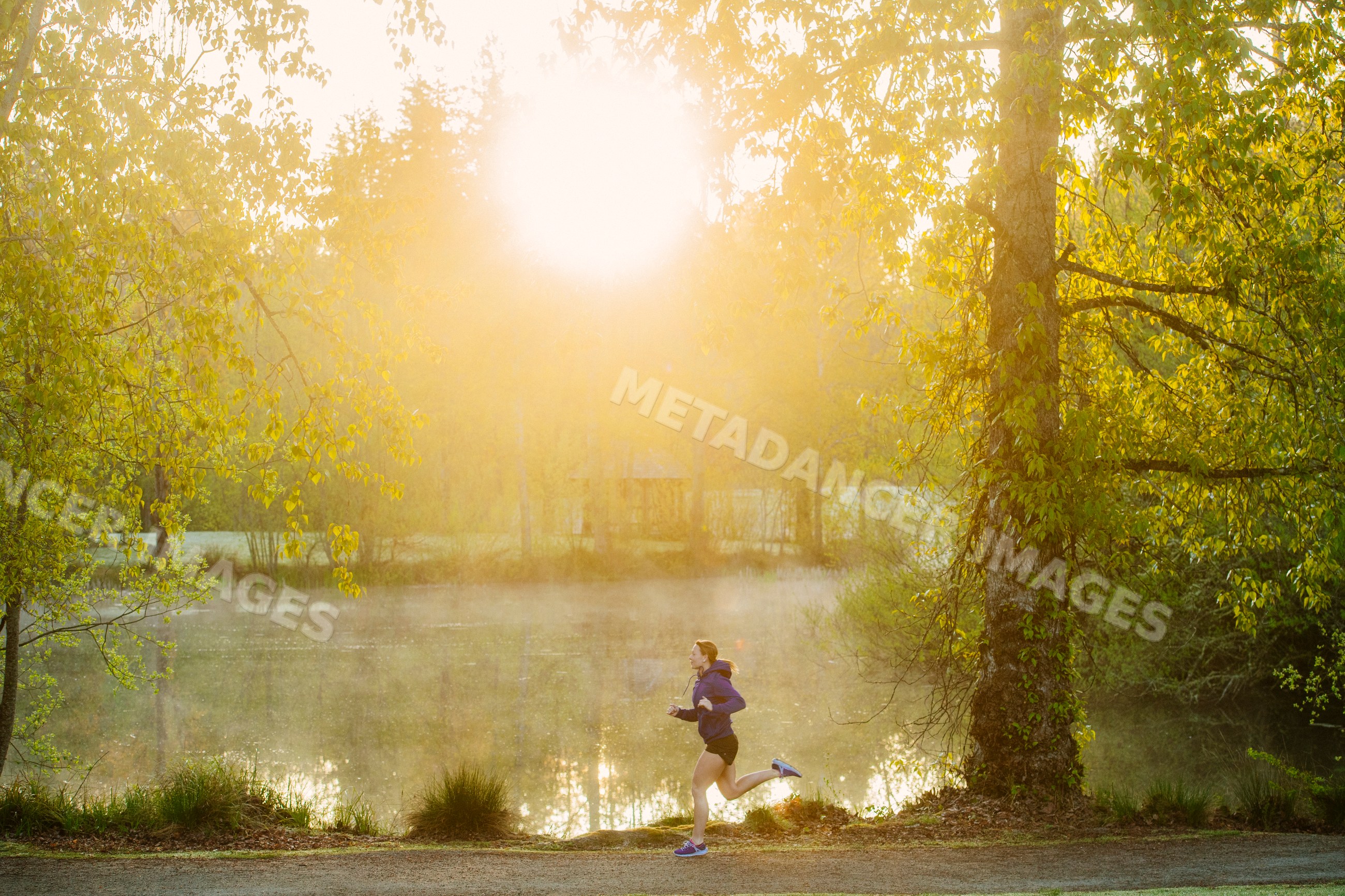 White runner jogging on trail in park at misty morning sunrise