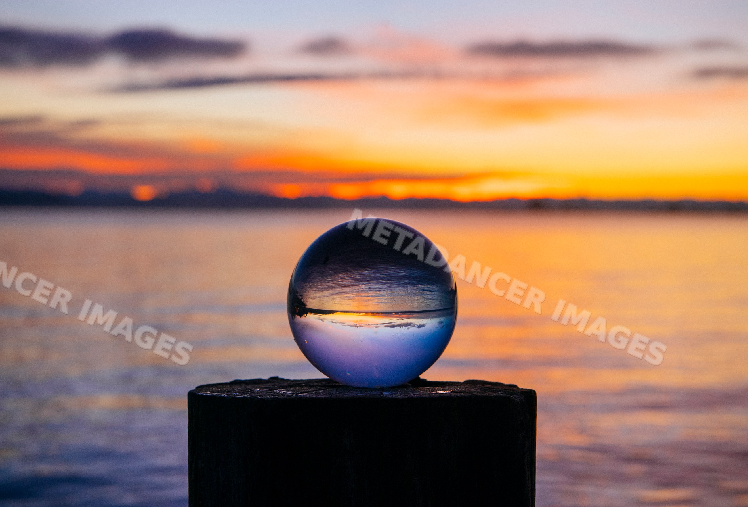 Crystal ball reflecting sunset over water