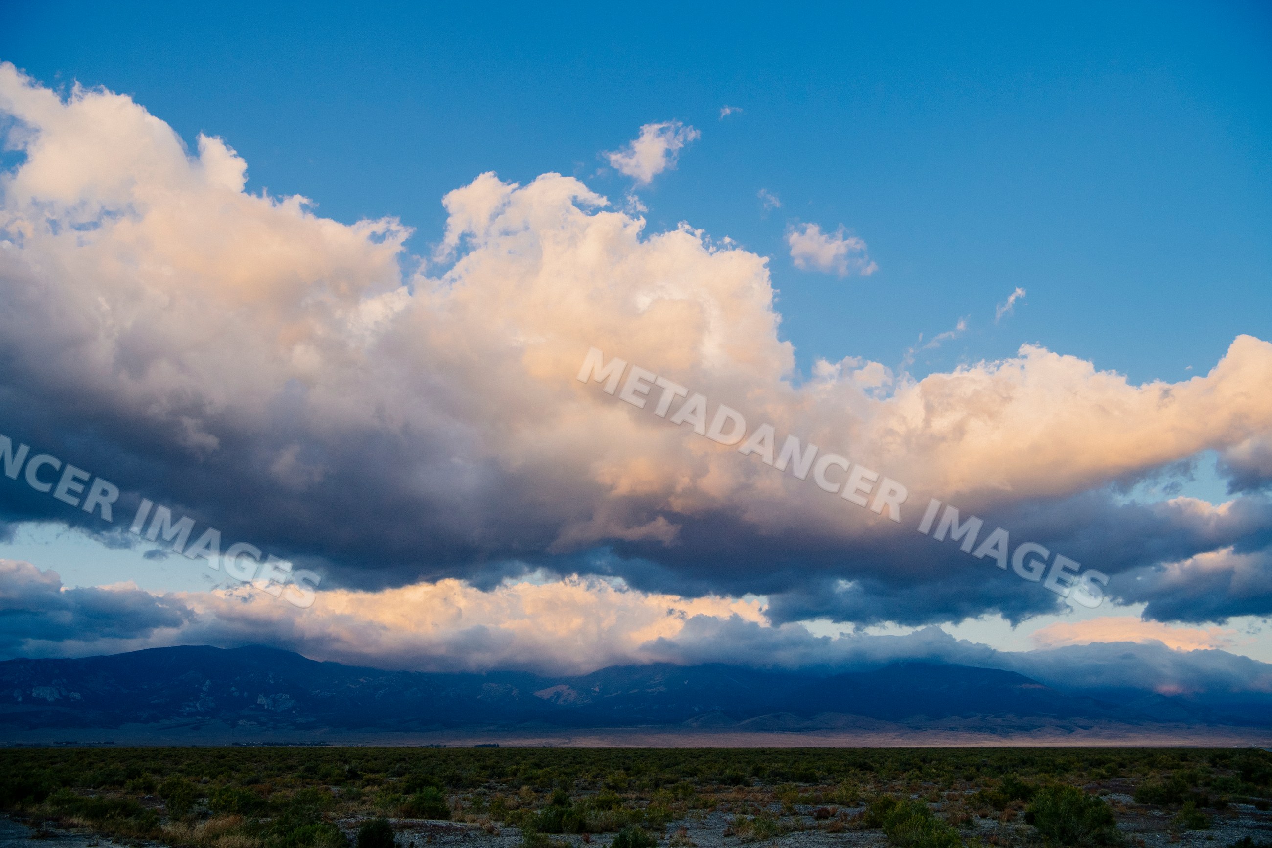 Clouds over Nevada mountain range and shrubland landscape at sunset