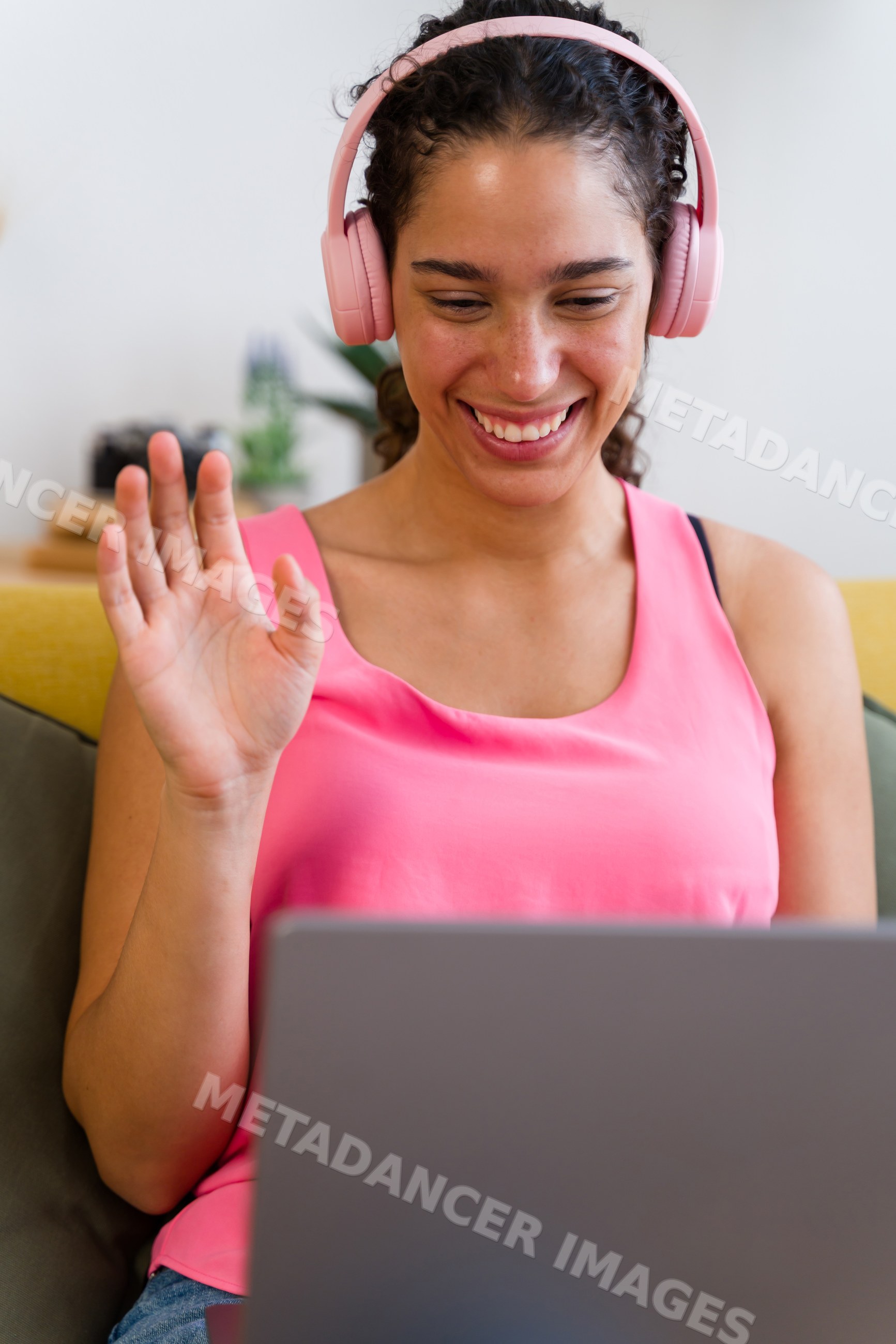 A Hispanic woman smiles and waves