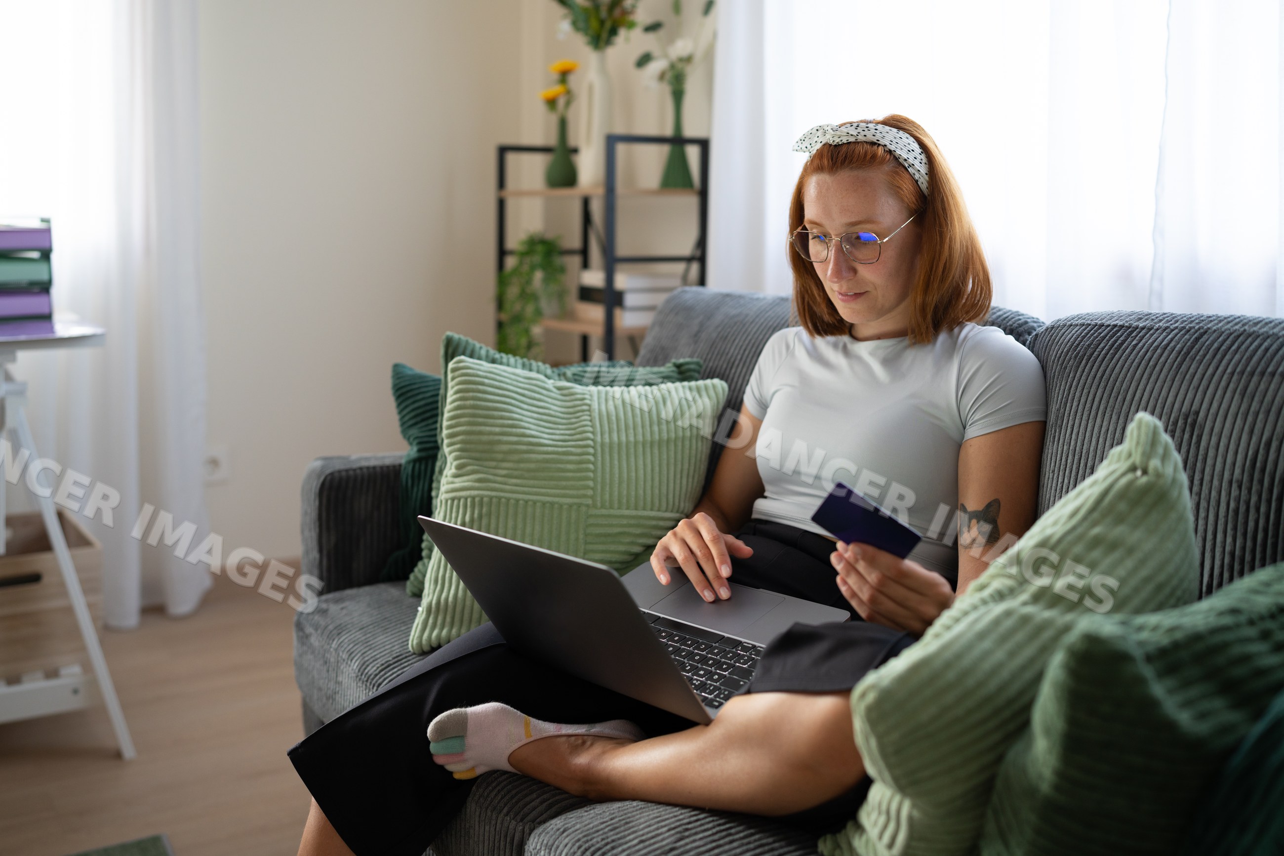 A white woman shops online at home using a laptop and a credit card