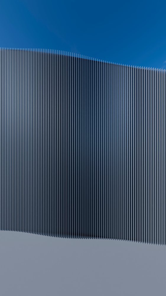 Curved metal fence with vertical bars against blue sky outdoors