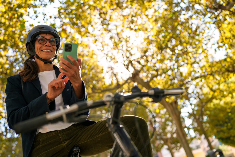 Hispanic woman on bicycle using smartphone