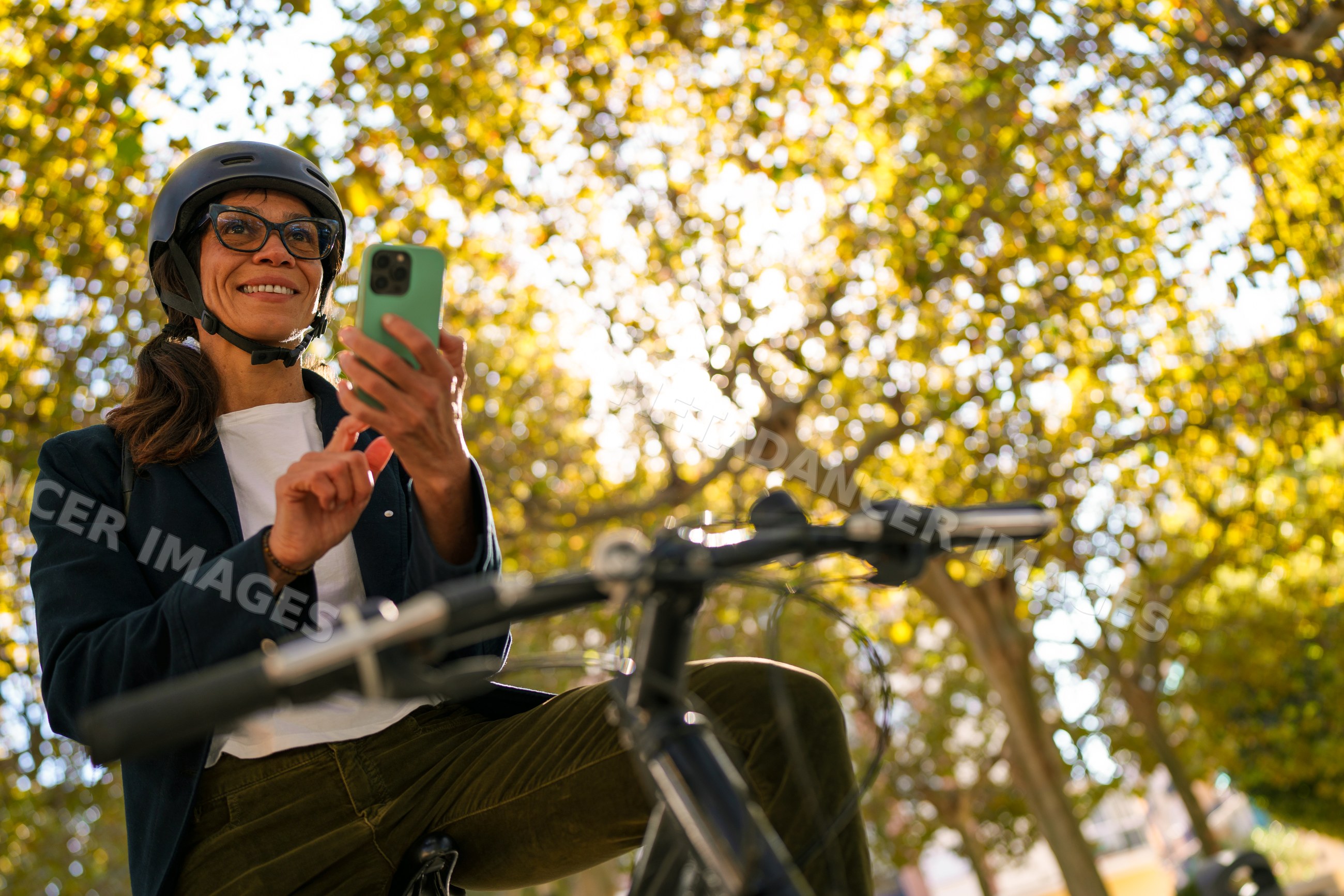 Hispanic woman on bicycle using smartphone