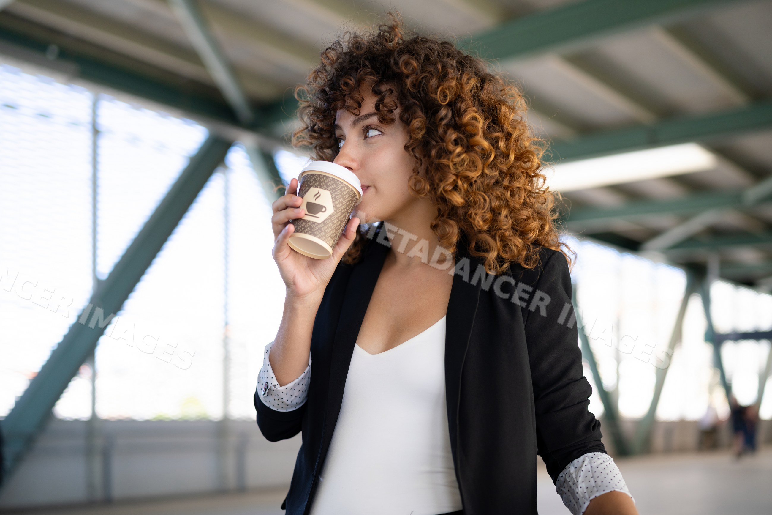 White woman drinking coffee from paper cup in urban outdoor space