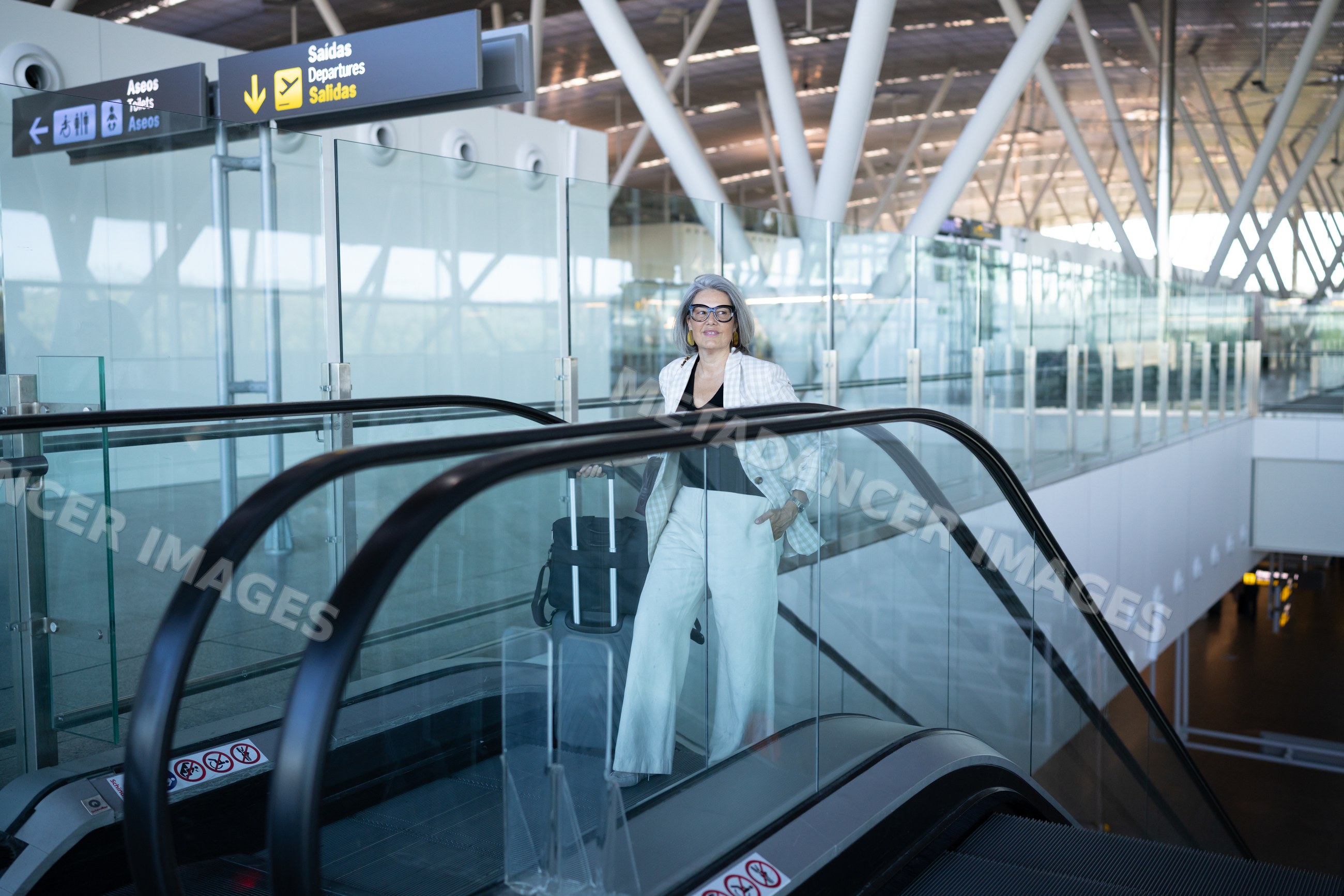 Businesswoman riding escalator toward departures at Madrid airport