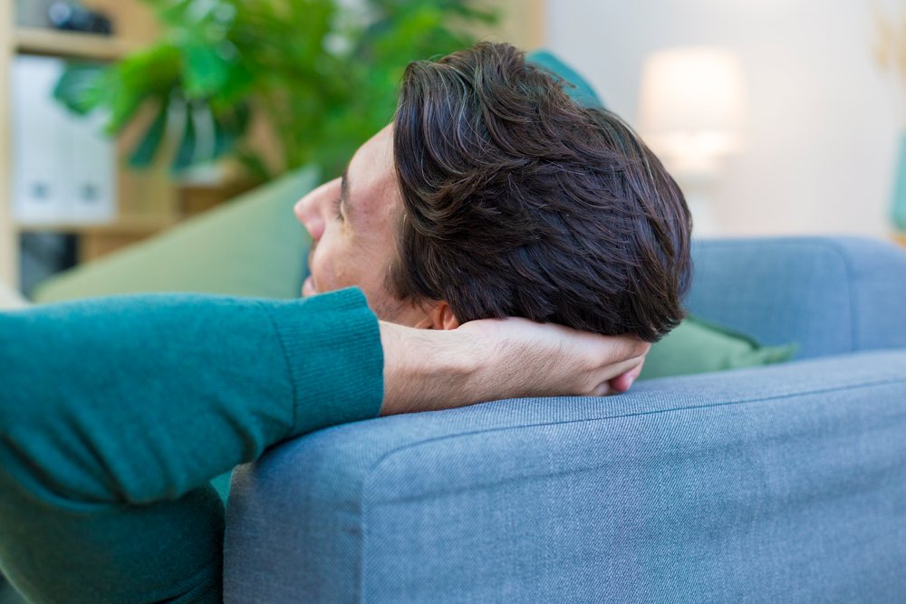 White man relaxing on a blue sofa in a home interior