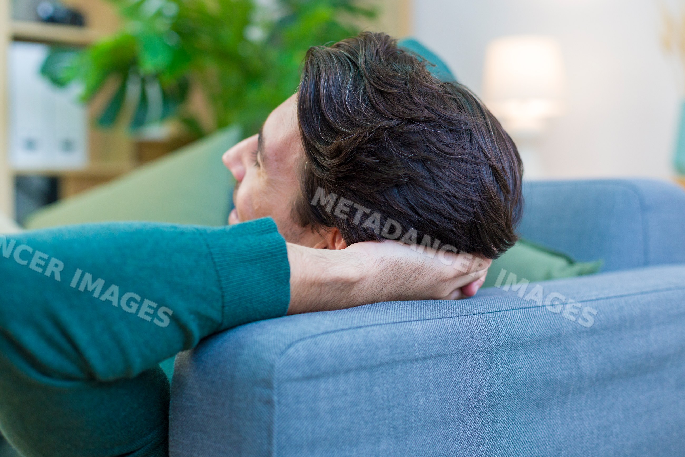 White man relaxing on a blue sofa in a home interior