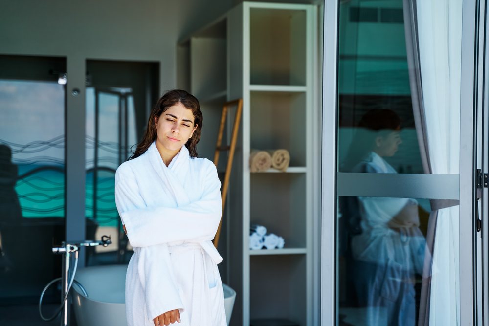 A woman in a white bathrobe relaxes inside a serene spa setting