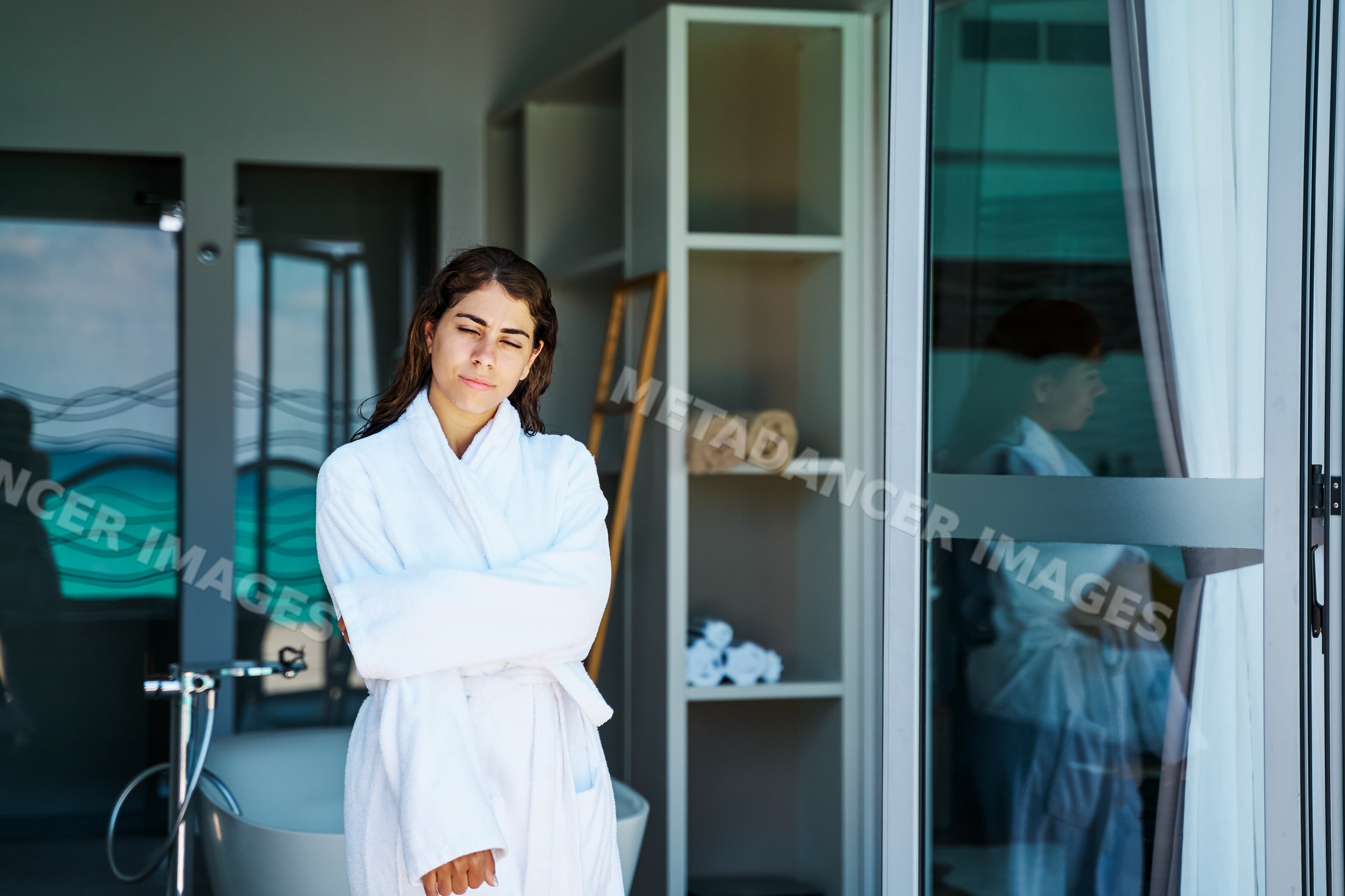 A woman in a white bathrobe relaxes inside a serene spa setting
