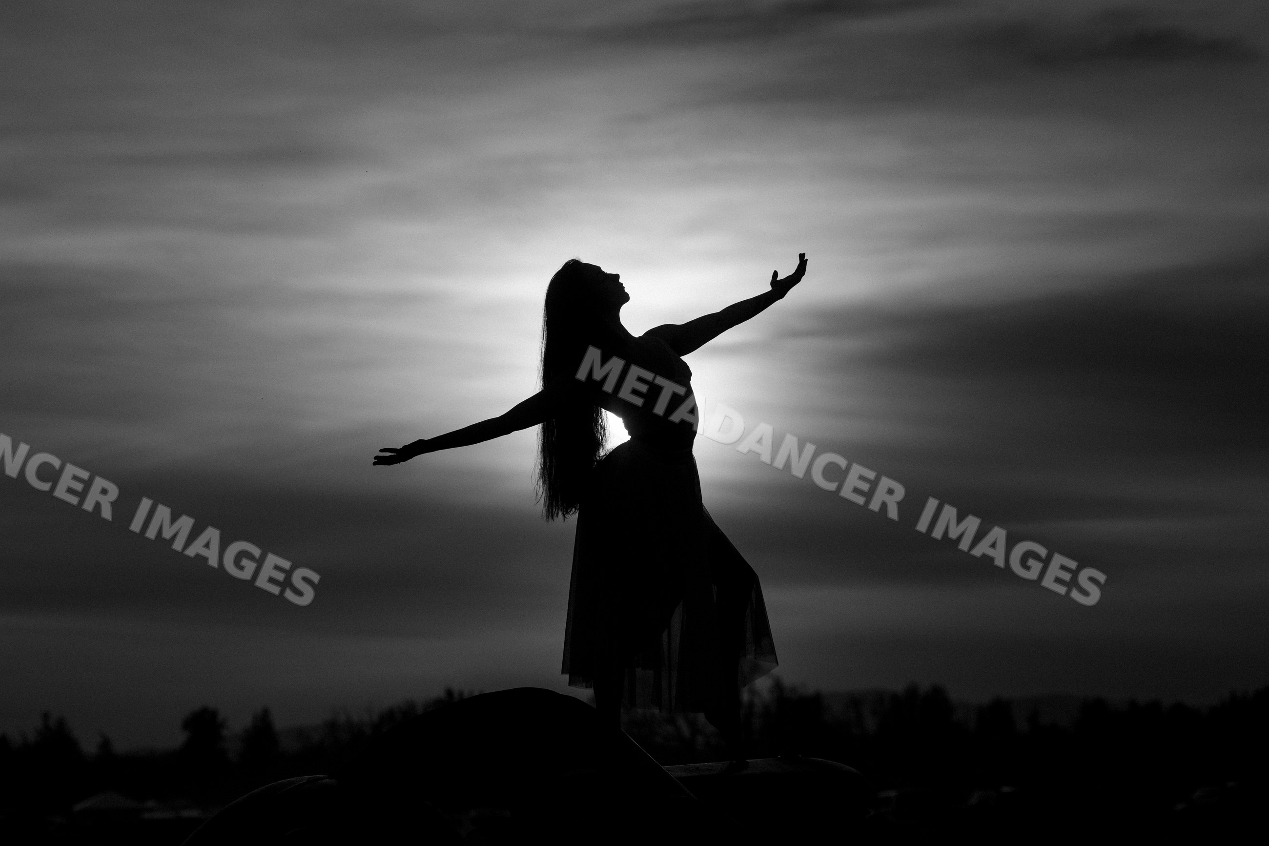 Silhouette of white woman dancer posing gracefully at sunset outdoors