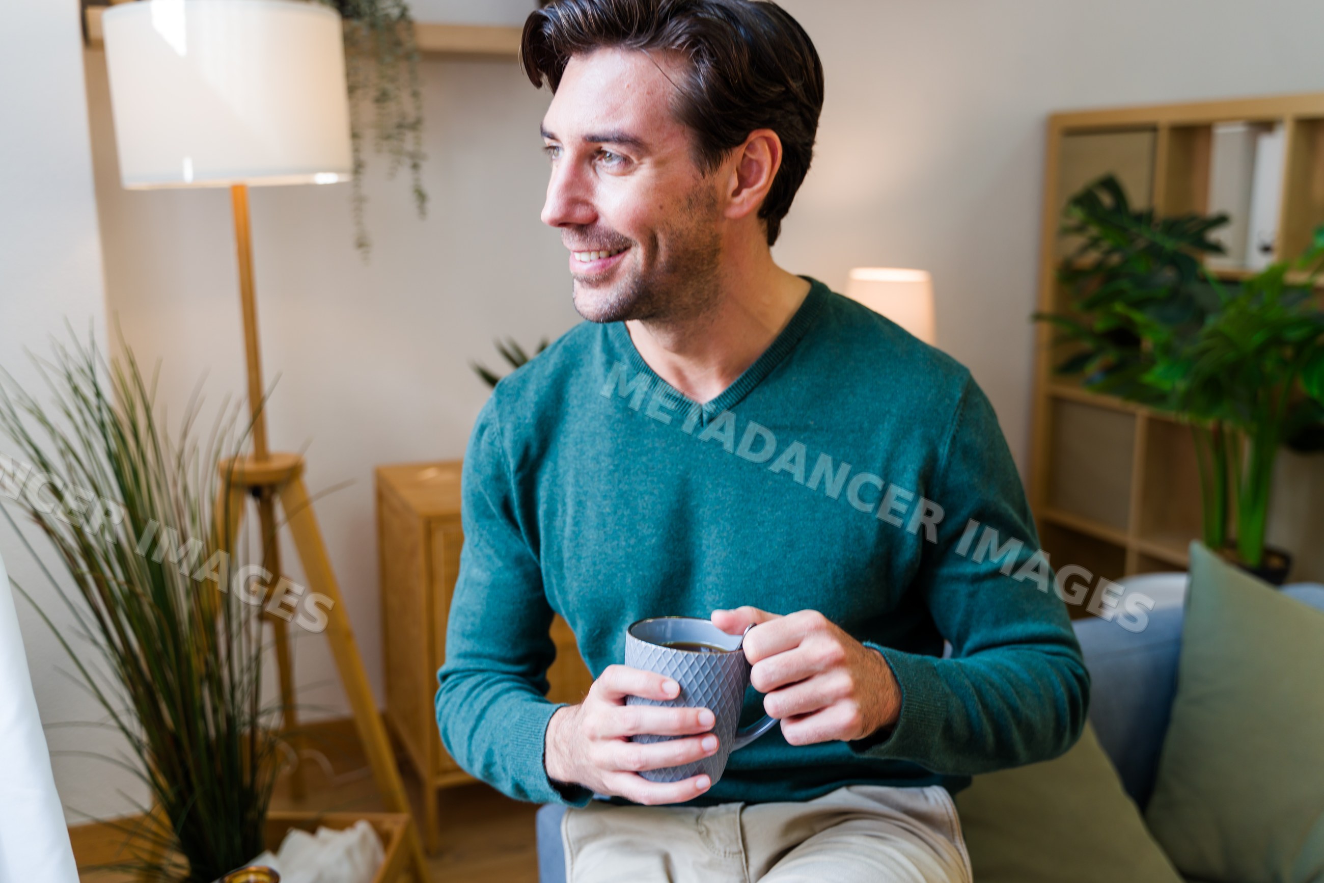 White man holding a mug and smiling in a cozy living room