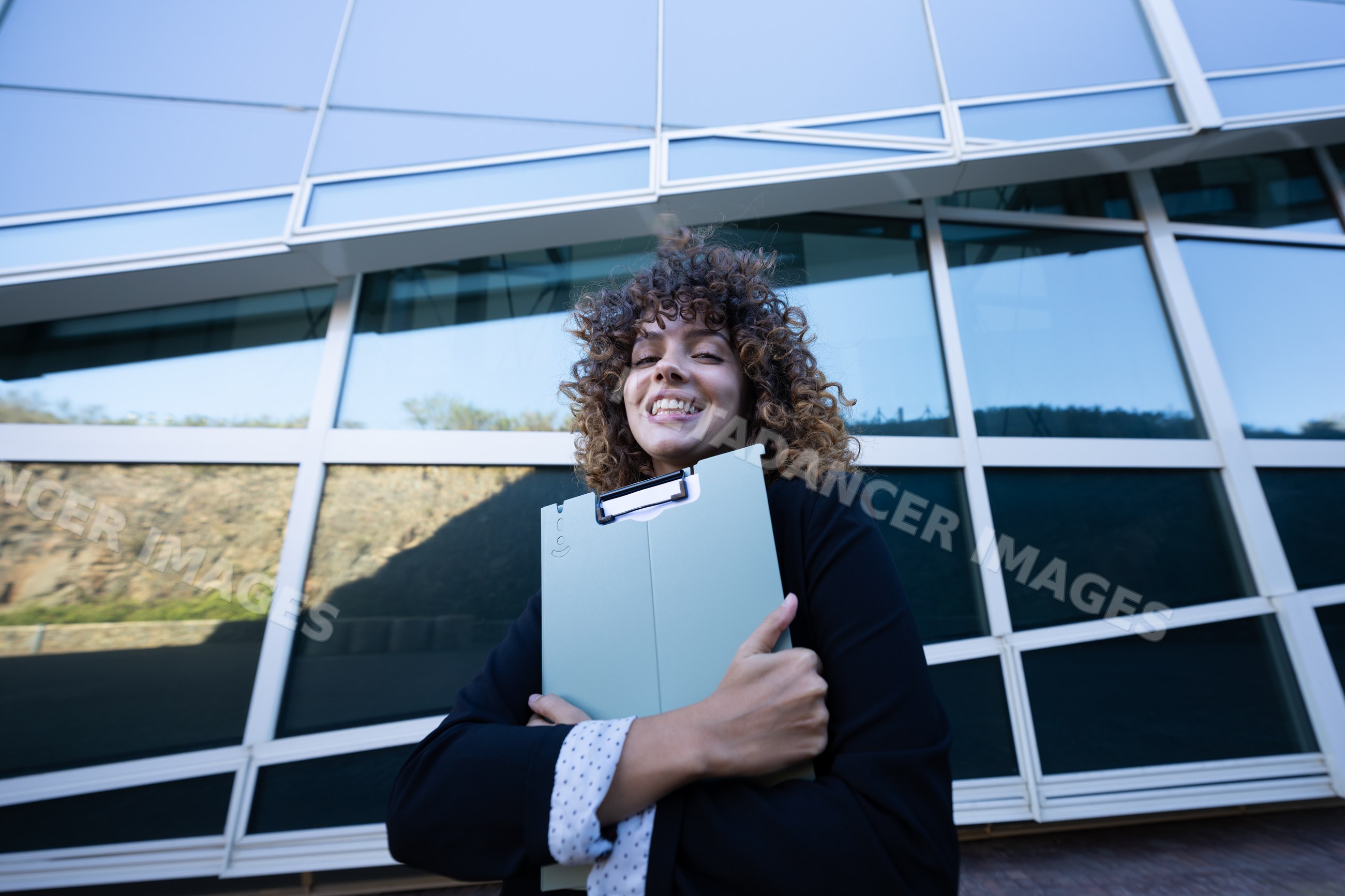 Businesswoman holding folder outside modern building