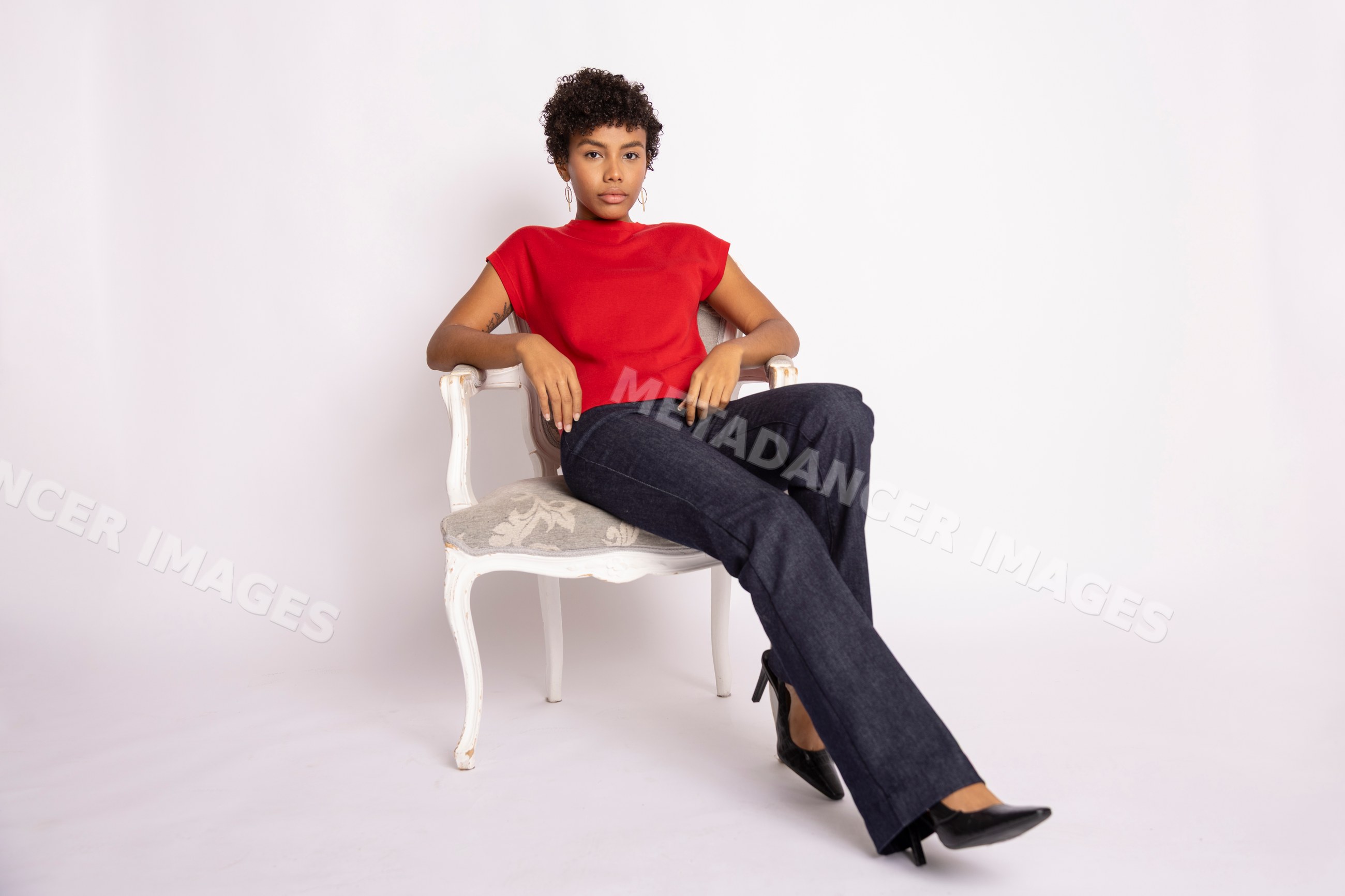 Hispanic woman sitting on white chair wearing red top and black pants