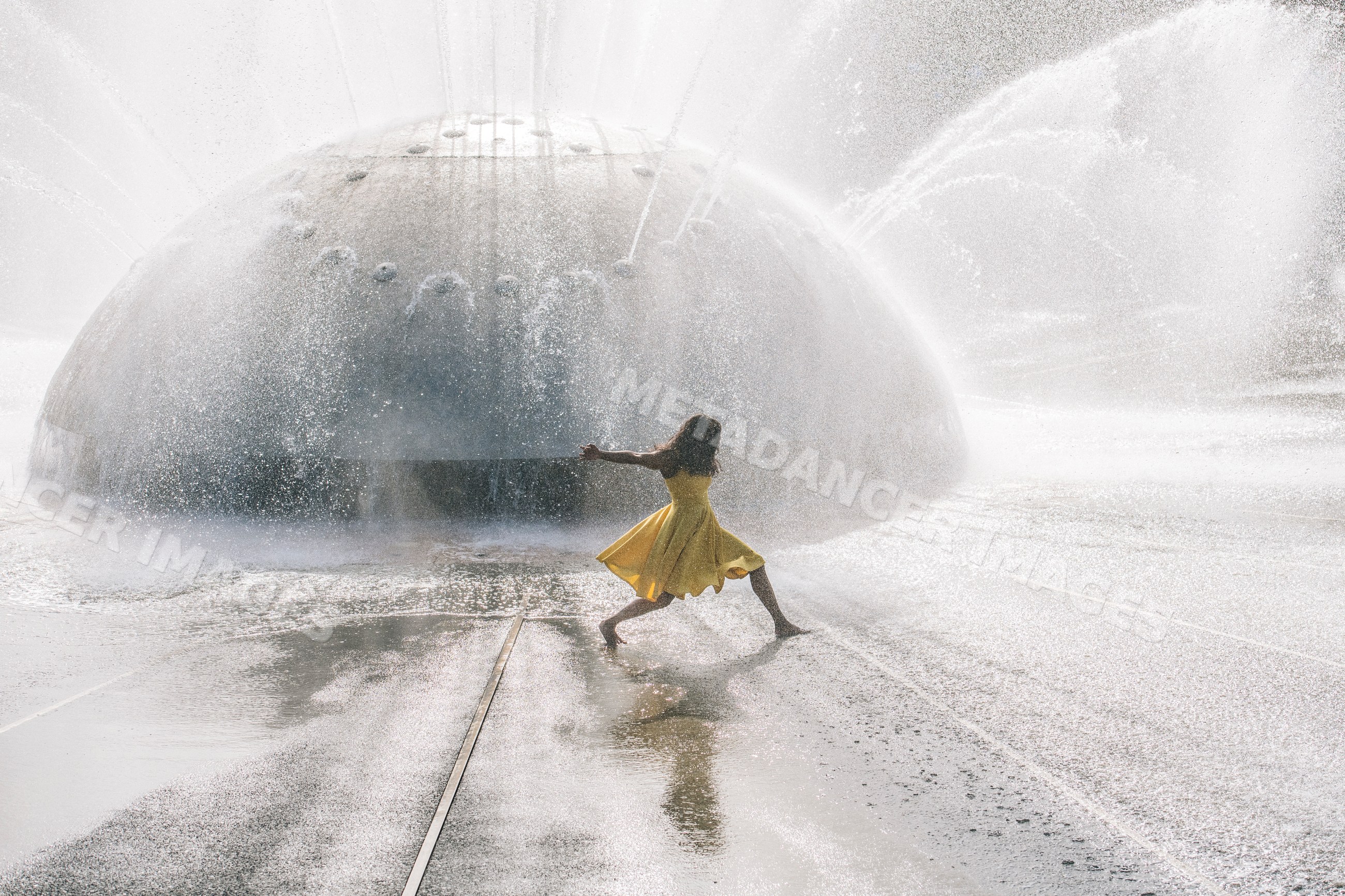South Asian girl dancing in water fountain spray outdoors
