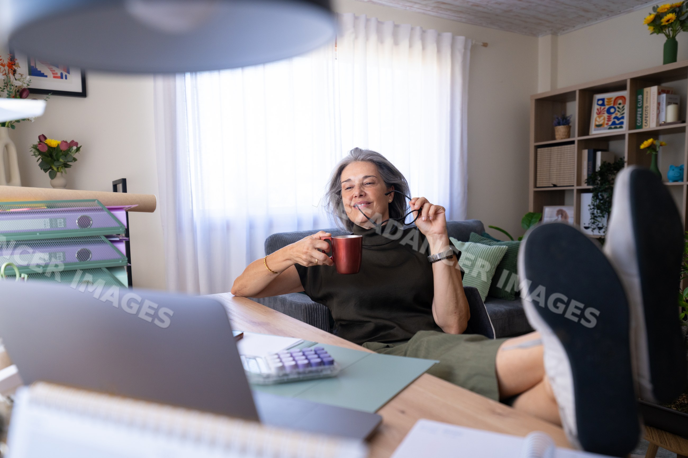 White woman relaxing with coffee in home office setting in a office