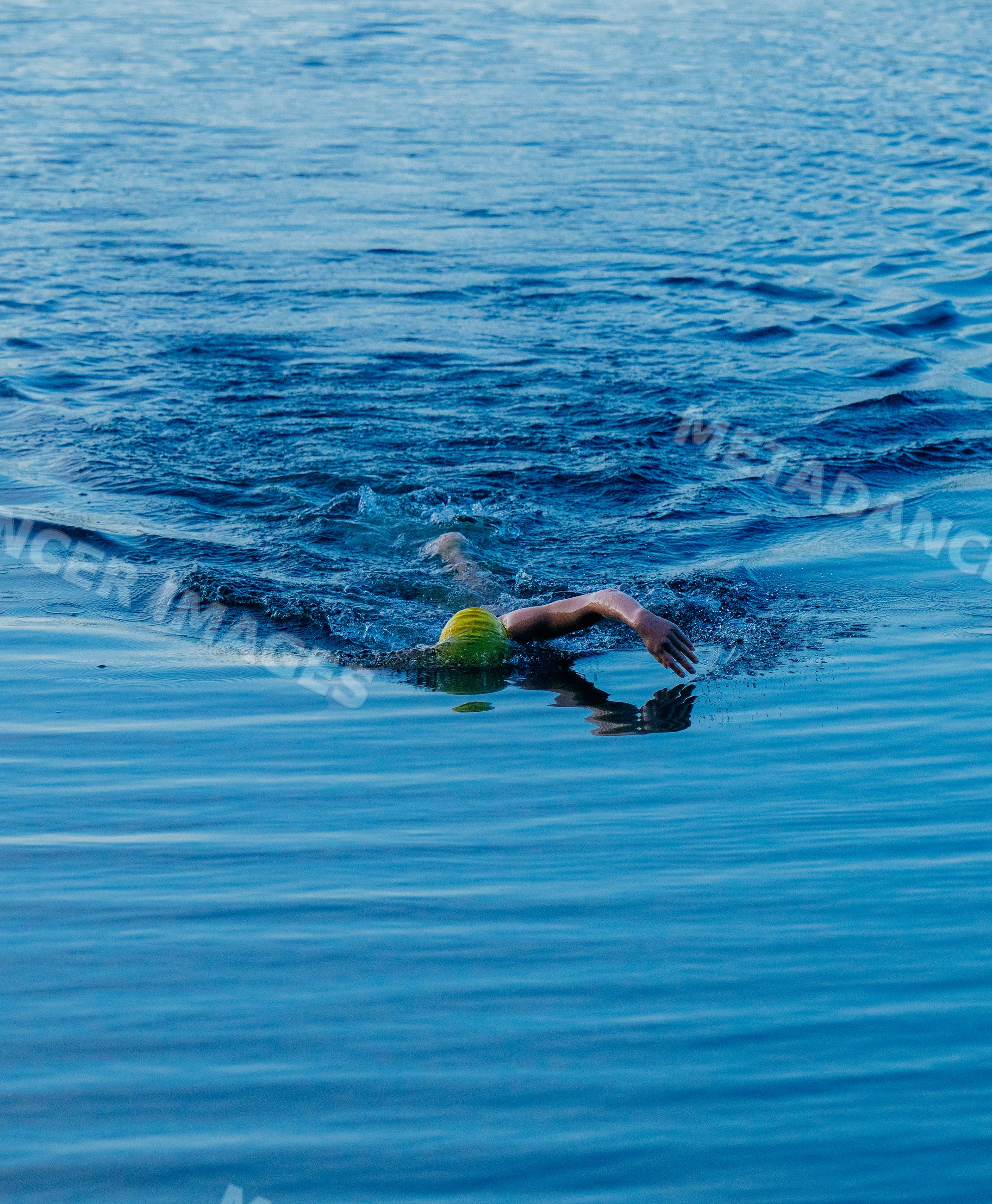 White swimmer performing freestyle stroke in open water lake