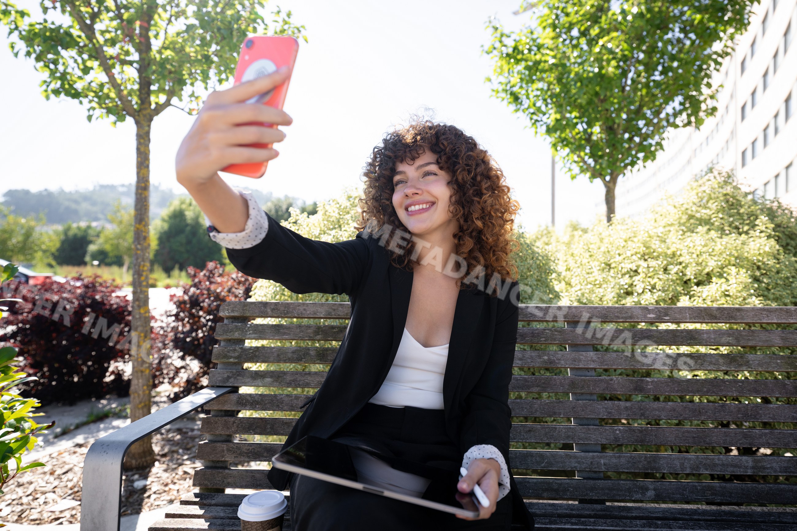 White woman taking a selfie with smartphone on outdoor bench