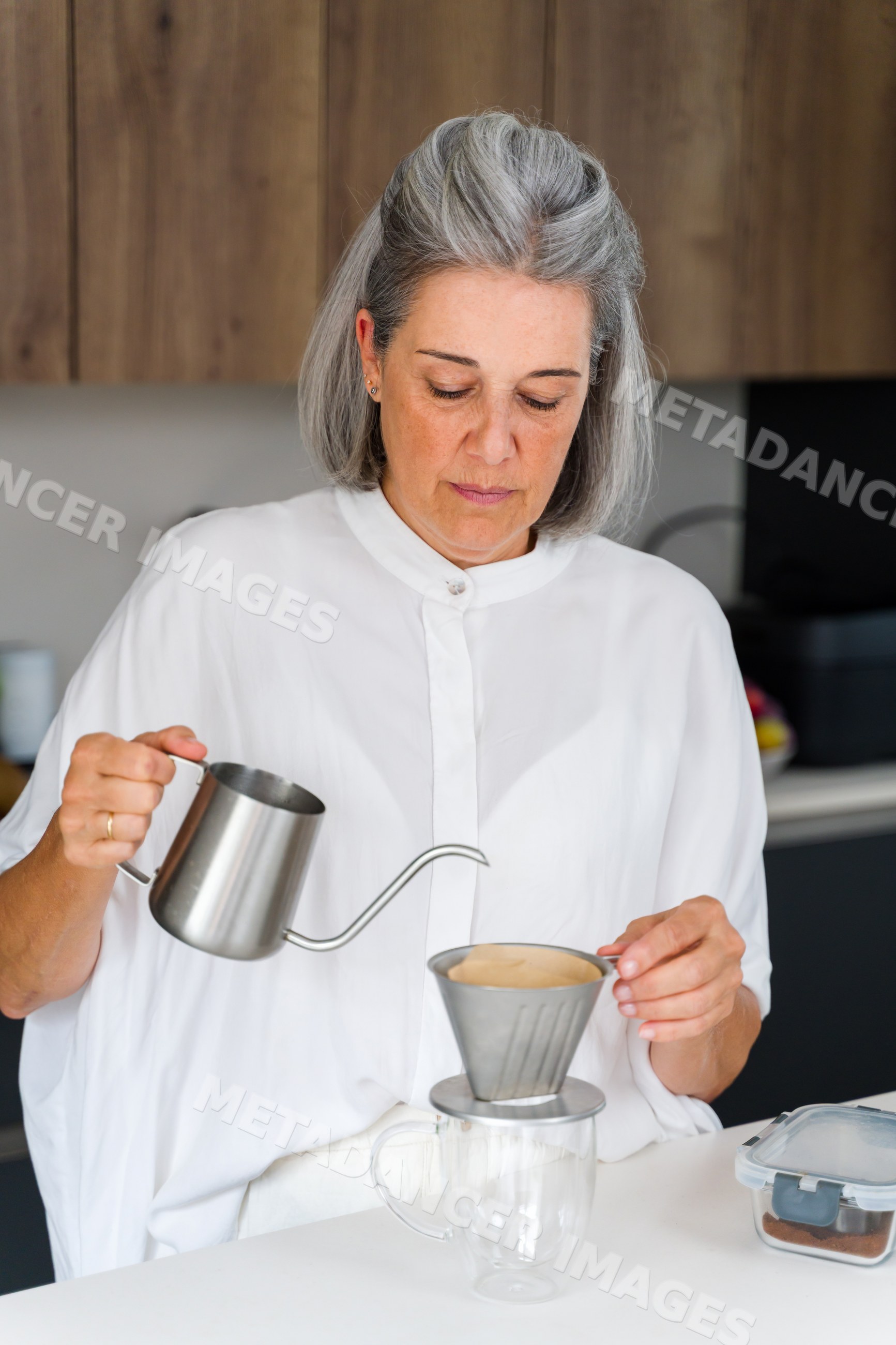 White Woman making drip coffee in kitchen with stainless steel kettle