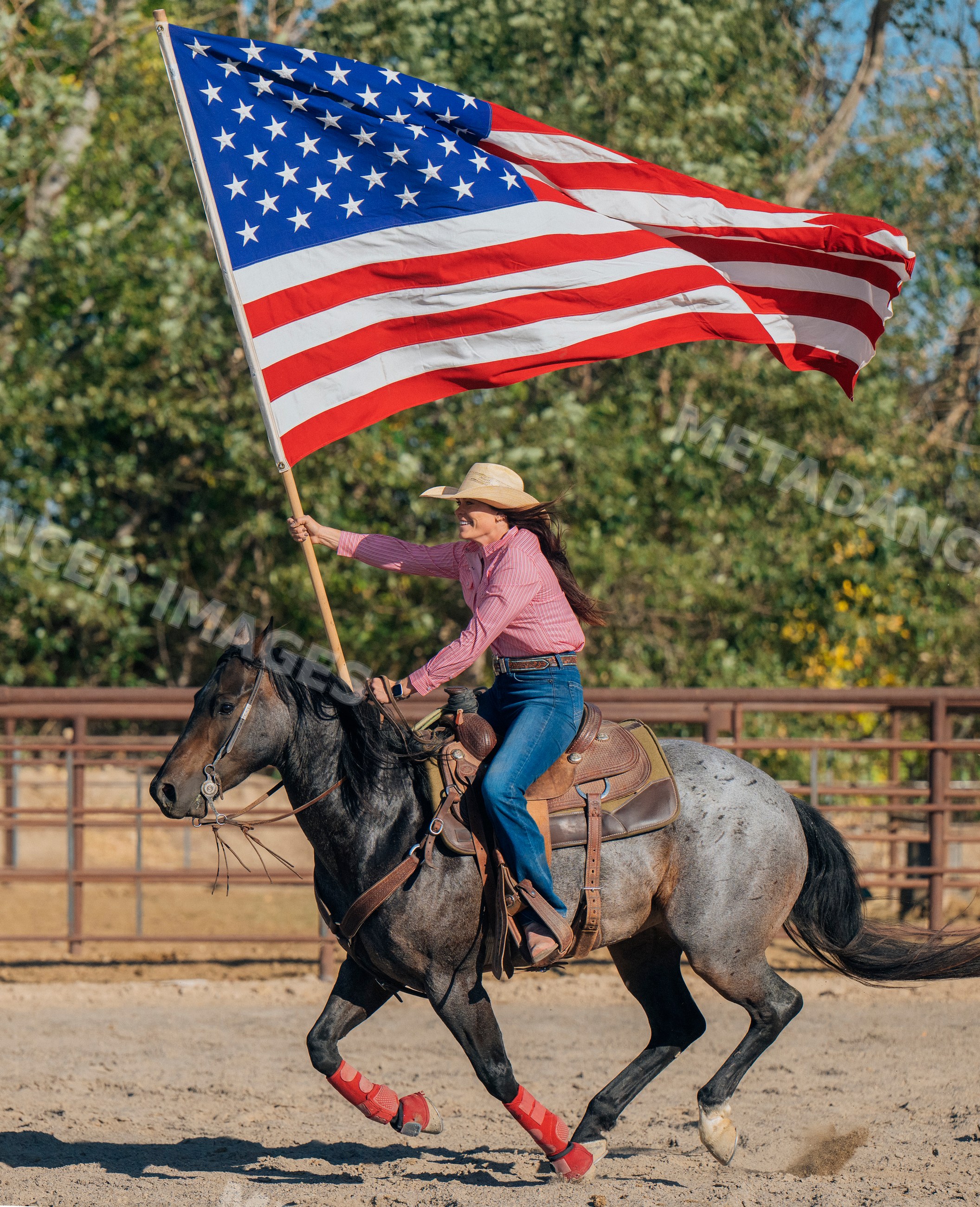 White woman riding a horse holding an american flag outdoors