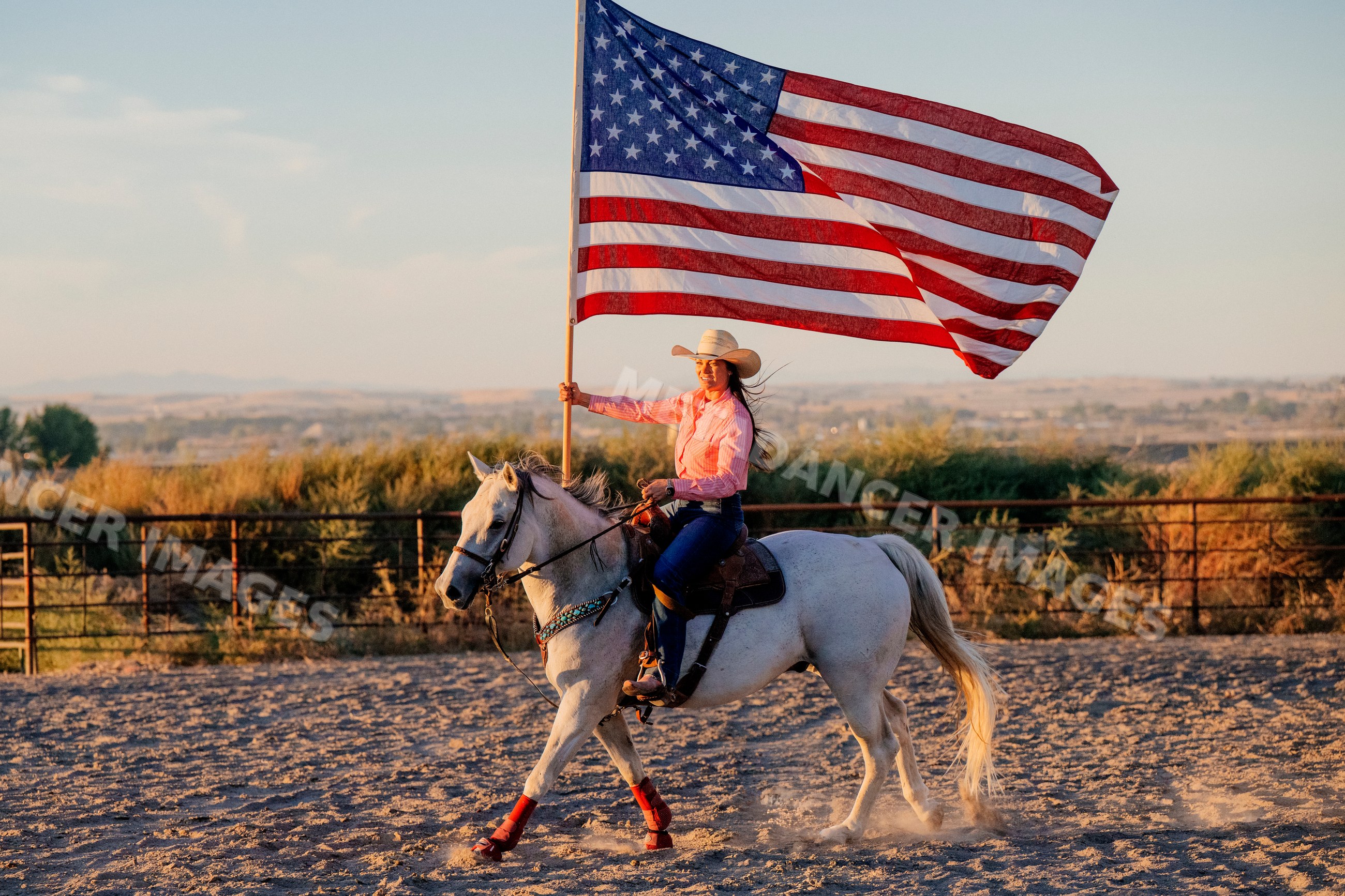 Woman riding white horse carrying american flag